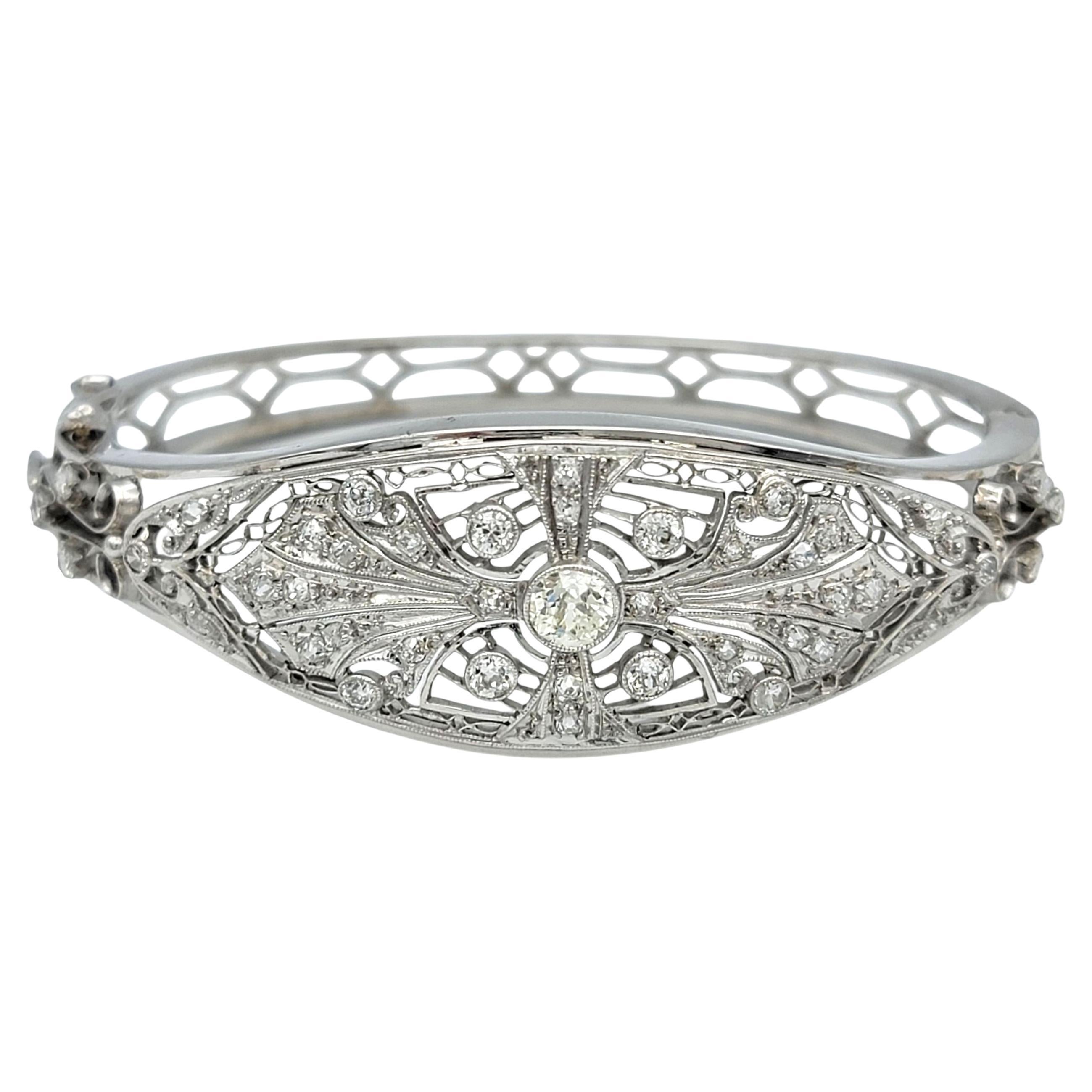 Dieser exquisite Vintage-Armreif mit Scharnier besticht durch seine zeitlose Eleganz und sein feines, detailliertes Design mit funkelnden Diamanten. In der Mitte ruht ein alt-europäisch geschliffener Diamant, der in einer Lünette gefasst ist, um