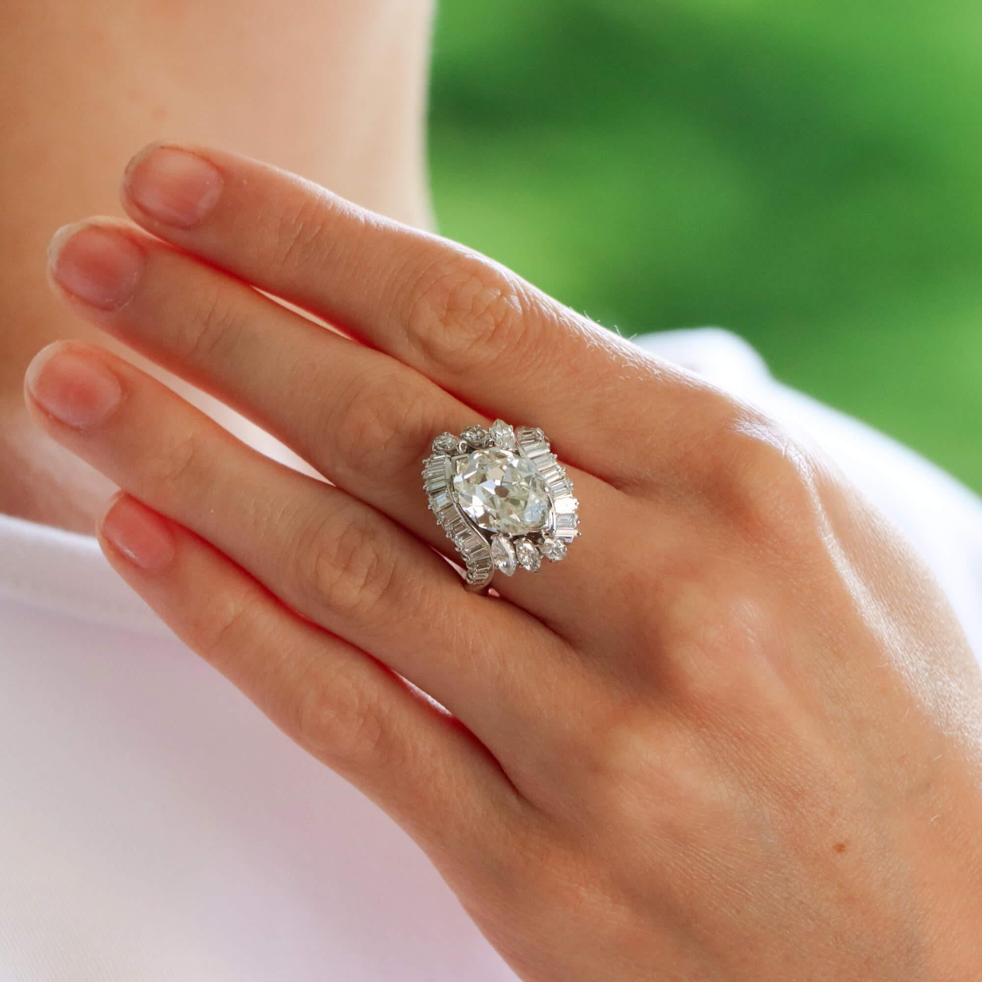 A beautiful old cut marquise cluster ring set in platinum.

The ring is predominately set with a highly unique and rare to find old cut marquise stone which is securely 6-claw set in a decorative mount. To each side the marquise is highlighted by