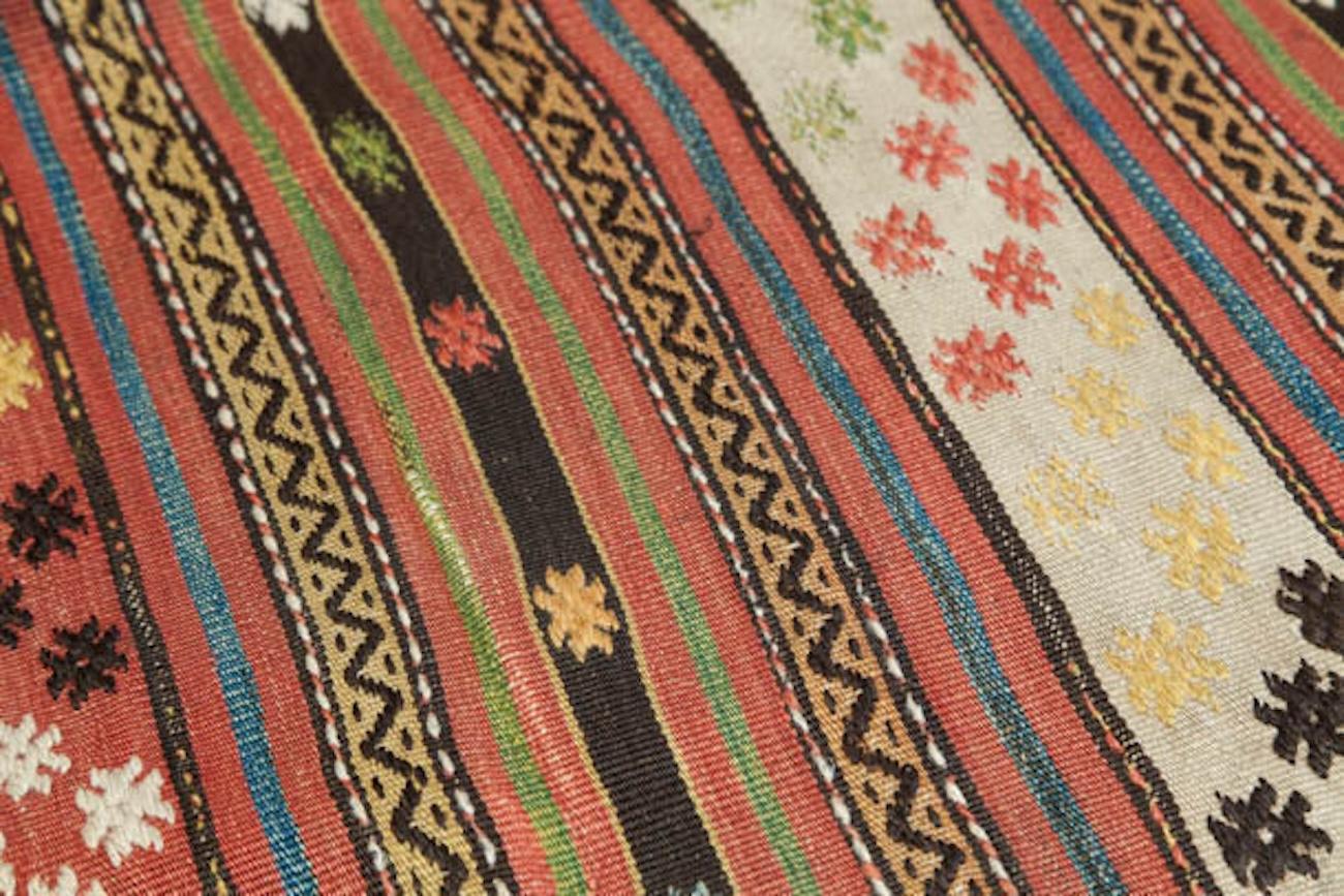 Questo kilim a righe orizzontali è grazioso e affascinante come un broccato di foglie autunnali o forse come un ruscello primaverile pieno di fiori galleggianti. La sua palette di colori evoca la delicata eleganza di un kimono giapponese, offrendo