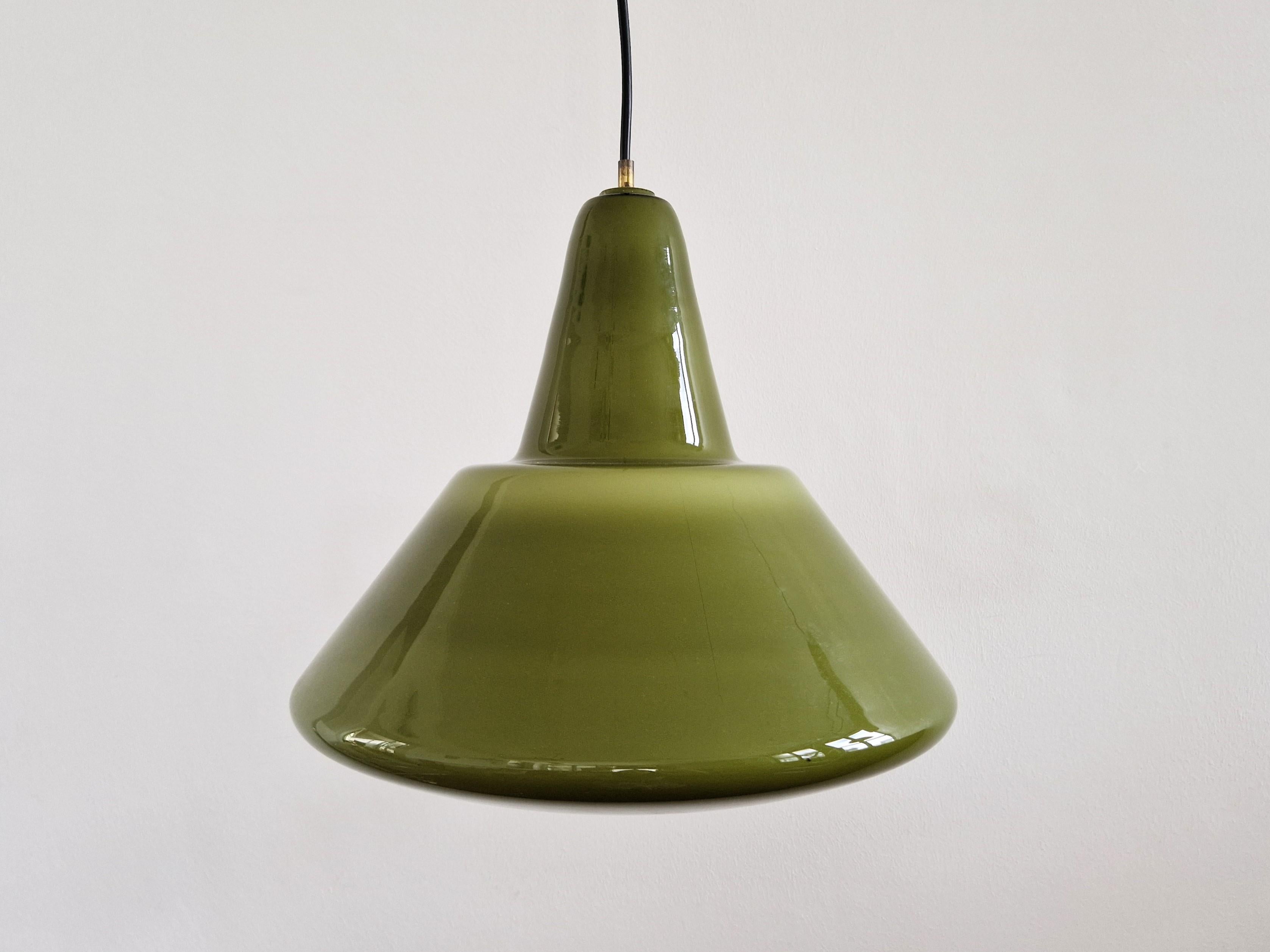 This stunning glass pendant lamp is a rare one we have not seen before. The combination of the elegant olive green colored glass and industrial shape makes it suitable in a variety of interiors. The lamp has a white glass inside and when lit it