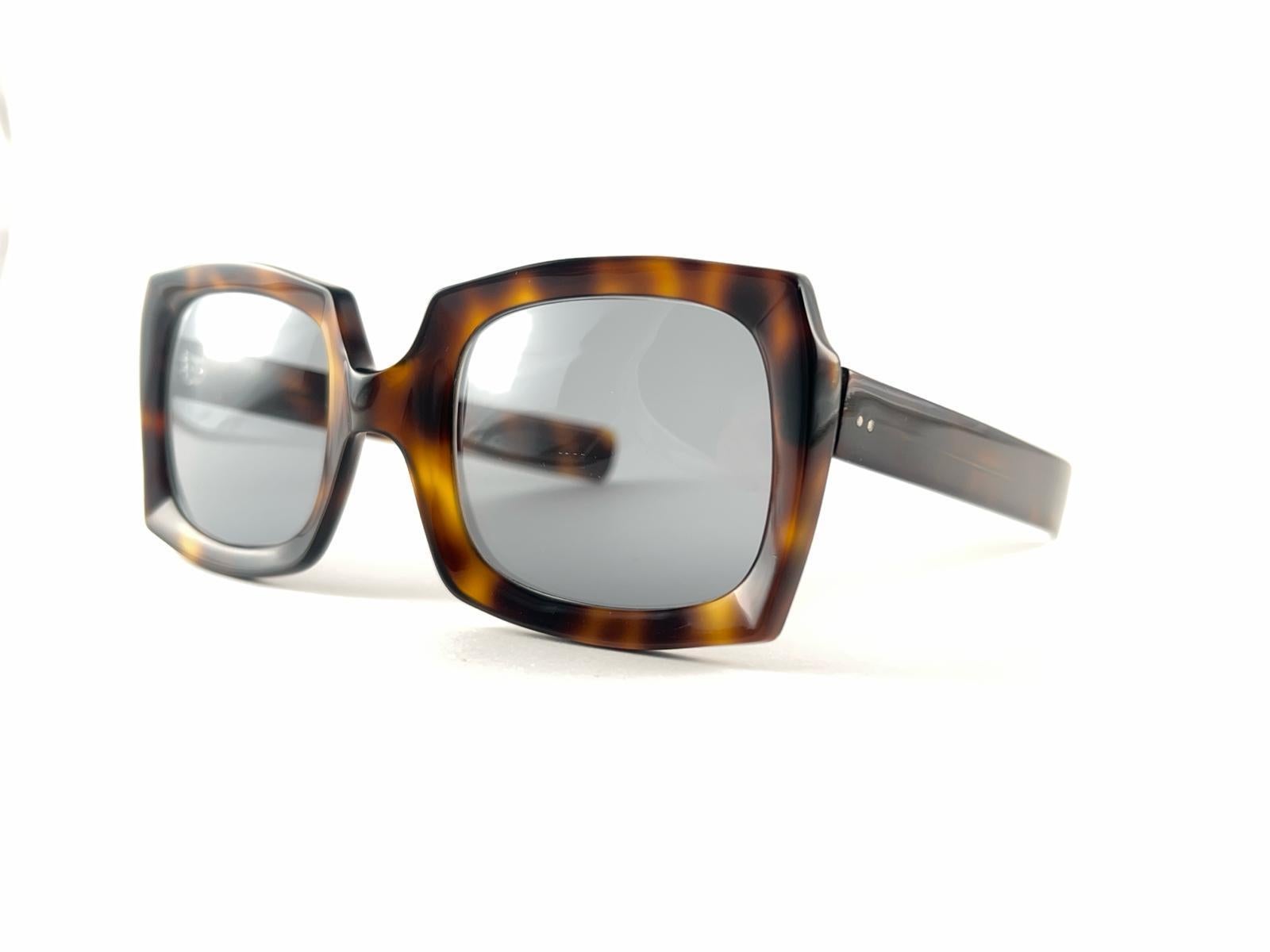 Robuste dunkelschildpattfarbene Sonnenbrille in Übergröße von Oliver Goldsmith, die ein Paar dunkelgrüne Gläser einrahmt. 
Leichte Abnutzungserscheinungen am Rahmen aufgrund der Lagerung.


Hergestellt in England


Vorderseite                       