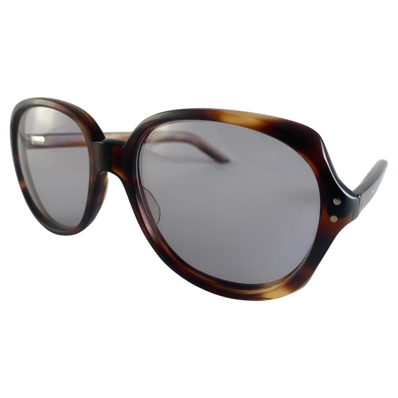 Lunettes de soleil Oliver Goldsmith surdimensionnées de couleur tortue foncée encadrant une paire de verres gris clair. 
Léger signe d'usure sur le cadre dû au stockage.


Fabriqué en Angleterre


Avant                                      16 Cms