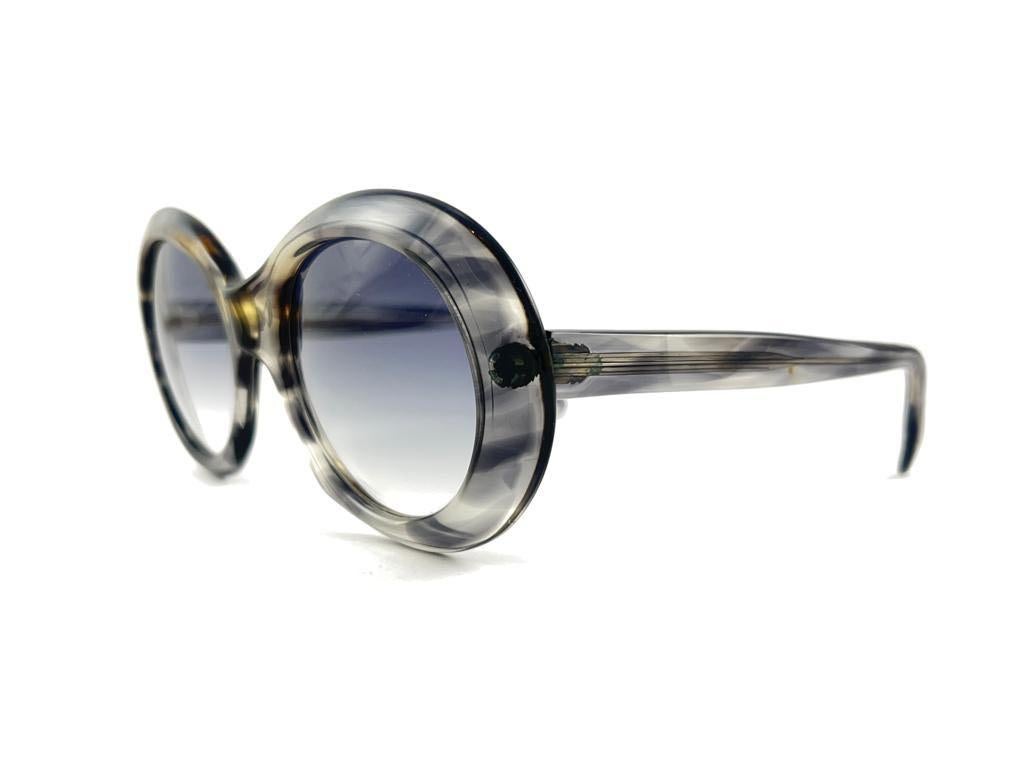 Oversized pair of Oliver Goldsmith sunglasses. 
Grey patern printed frame holding a pair of light lenses. 

This pair have minor sign of wear due to storage.

Handmade in England.


MEASUREMENTS

FRONT : 15 CMS

LENS HEIGHT : 5.2 CMS

LENS WIDTH :