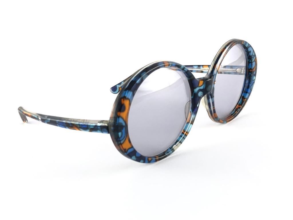 Oversized pair of Oliver Goldsmith sunglasses. 
Colored patern printed frame holding a pair of light grey lenses. 

This pair have minor sign of wear due to storage.

Handmade in England.


MEASUREMENTS

MEASUREMENTS 

FRONT : 15 CMS 

LENS HEIGHT :
