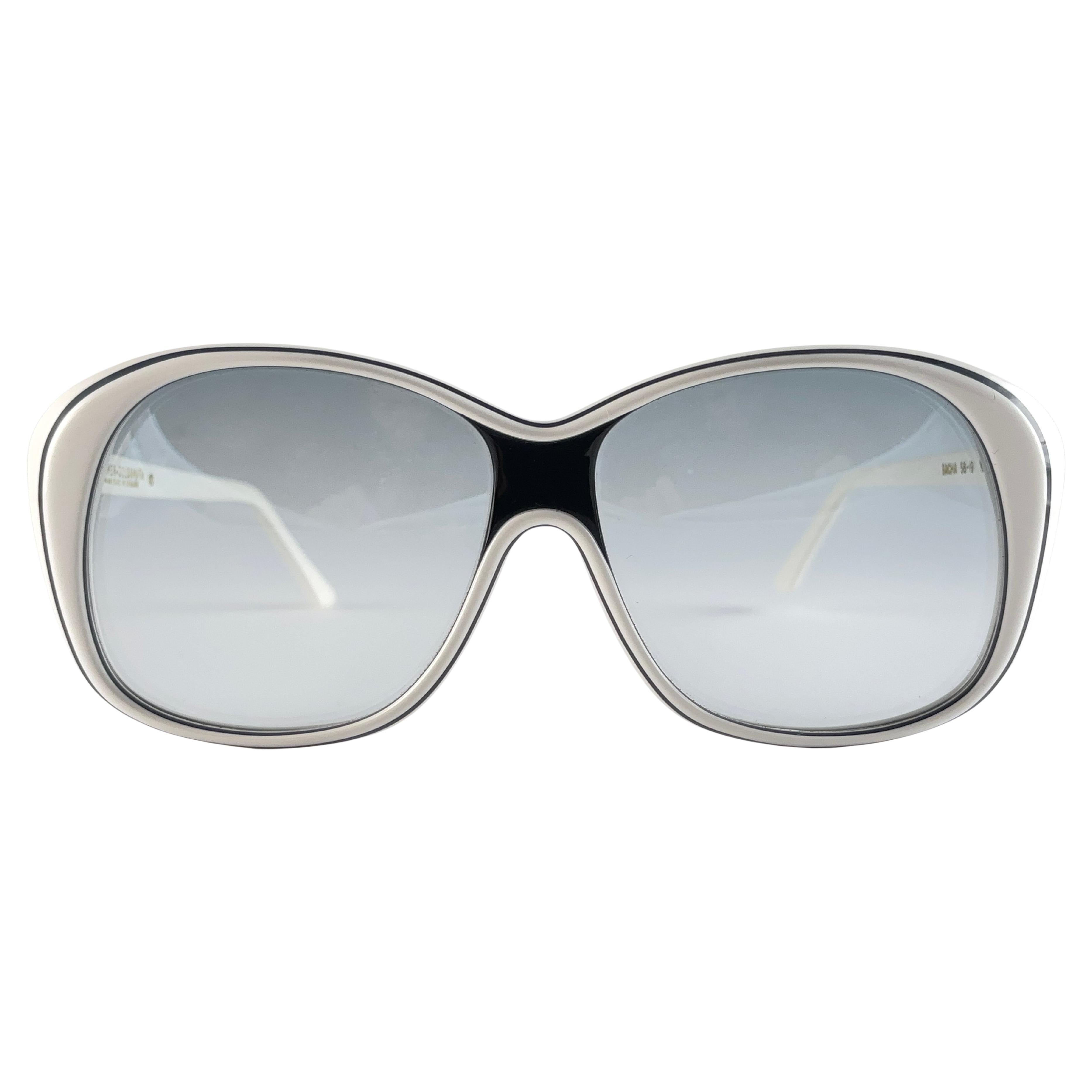 Paire de lunettes de soleil Oliver Goldsmith surdimensionnée. 

Cadre blanc et noir surdimensionné tenant une paire de  Lentilles dégradées légères. 

Cette paire présente des signes mineurs d'usure dus au stockage.

Fabriqué à la main en