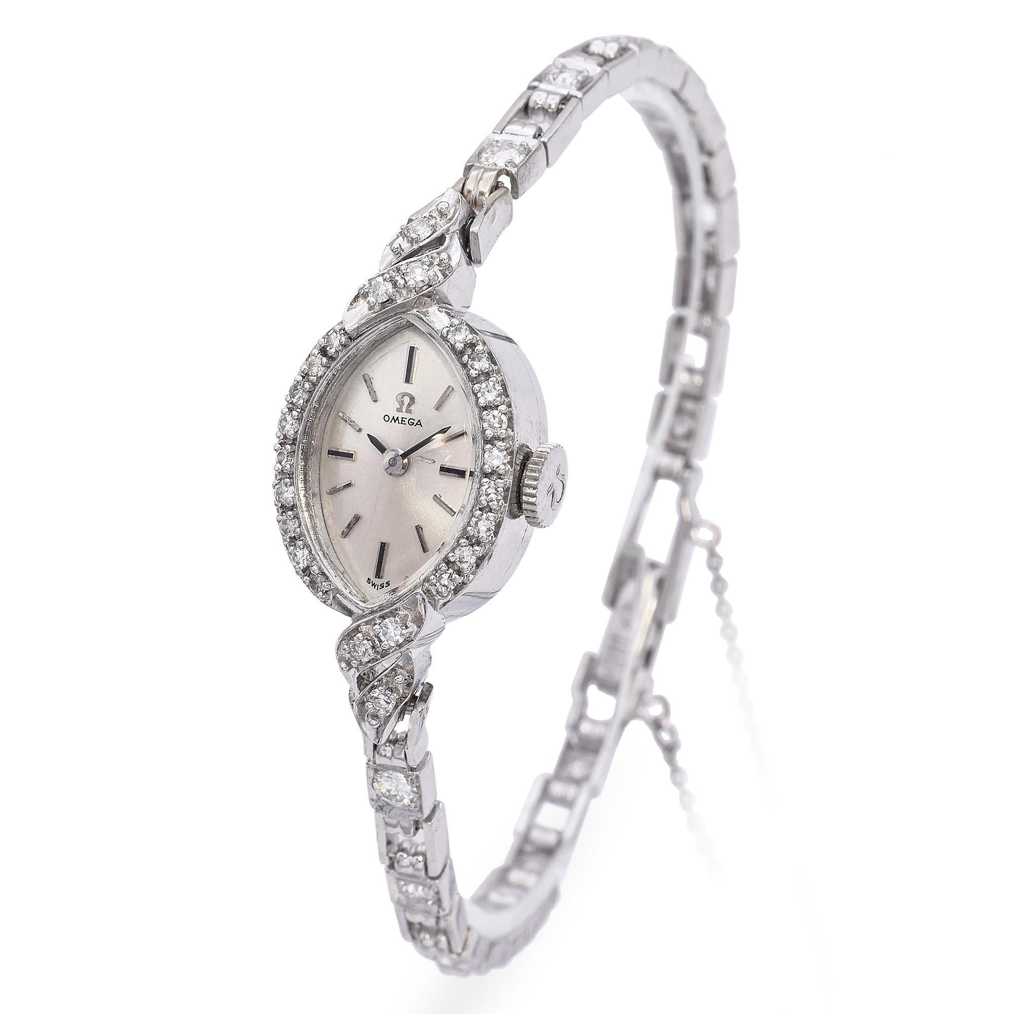 Elegant Mid 20th Century Omega White Gold Diamond Watch. This exquisite timepiece is crafted in white gold. The watch features a delicate oval face surrounded by a halo of sparkling diamonds. The bracelet is adorned with intricate diamond accents,