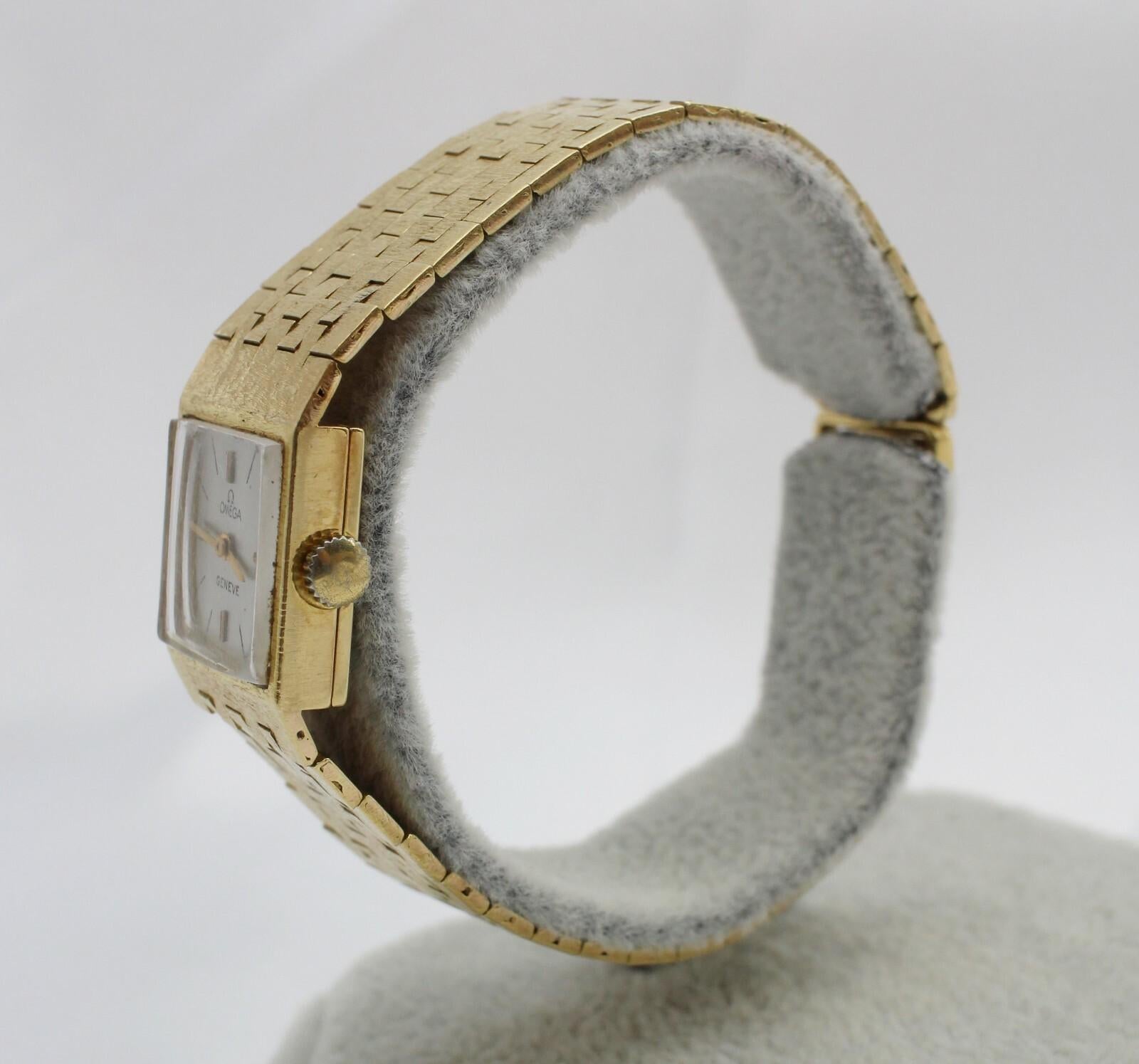 Diese alte Omega Genève Damenuhr ist ein beeindruckendes Beispiel für die Eleganz der Jahrhundertmitte und stammt wahrscheinlich aus den 1960er bis frühen 1970er Jahren. Die aus massivem 18-karätigem Gelbgold gefertigte Uhr verfügt über ein