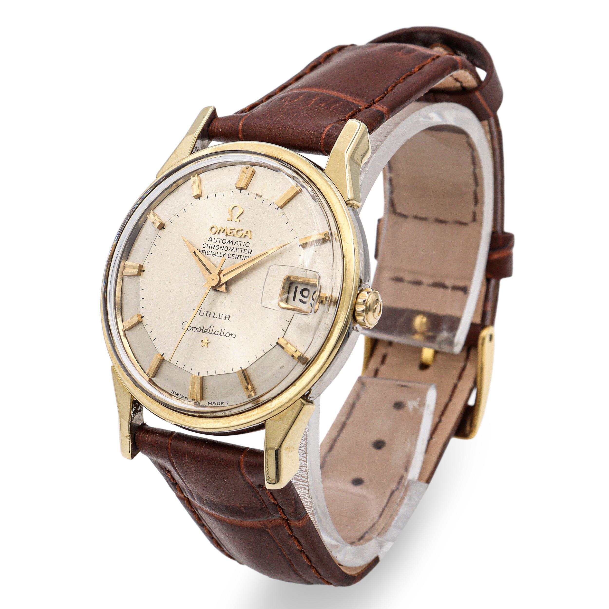 Un refinado reloj de pulsera vintage Omega Constellation para hombre, con caja de oro de 14 quilates y fondo de acero inoxidable adornado con el característico medallón del observatorio. La esfera plateada presenta una encantadora pátina envejecida,