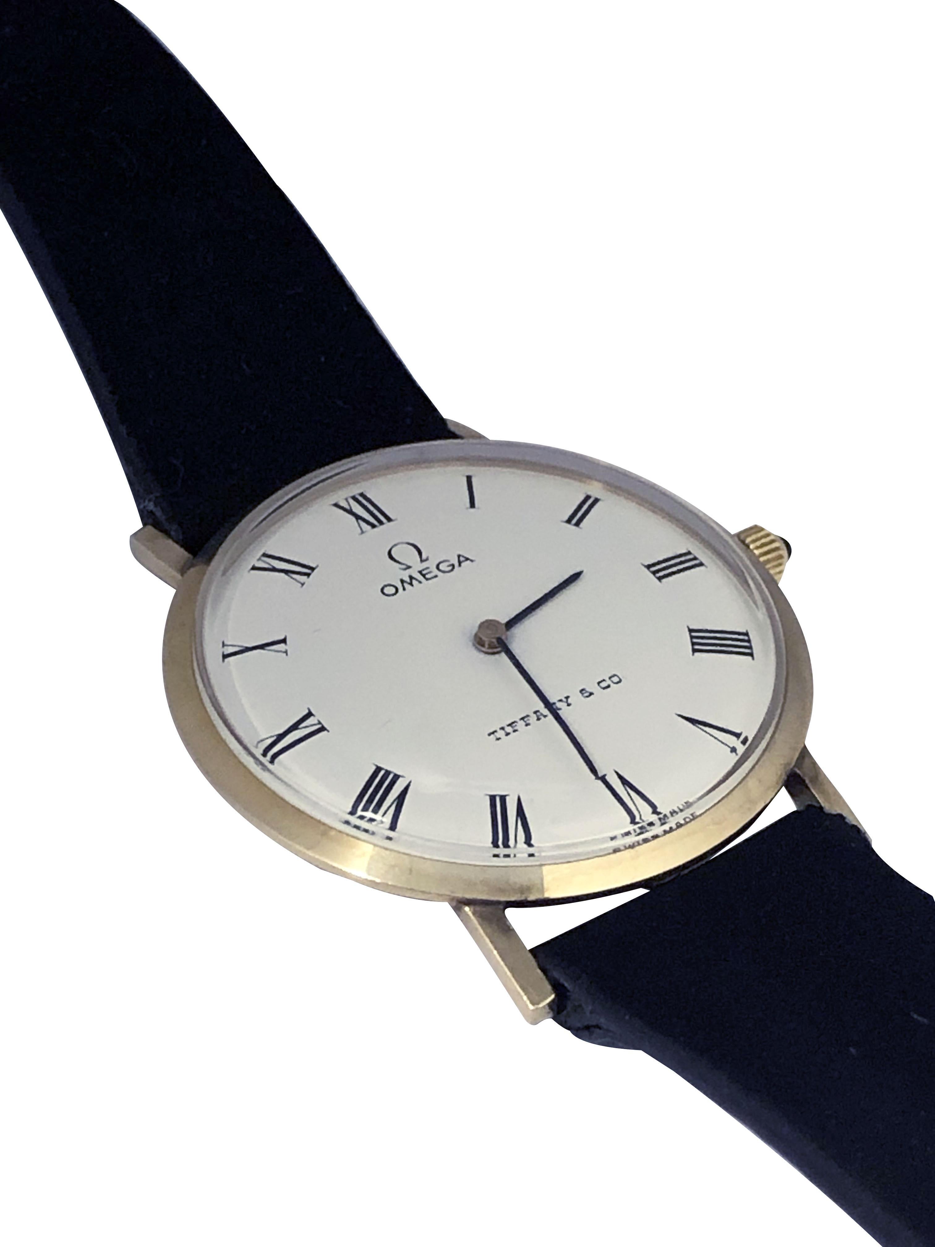 Circa 1980 Omega for Tiffany & Company Wrist Watch, 33 M.M. 2 piece 14k Yellow Gold 2 piece case, Caliber 625, 17 jewel, mechanical, manual wind movement, White Enamel dial with Black Roman numerals, Sapphire Crown.  Bracelet Omega en satin noir