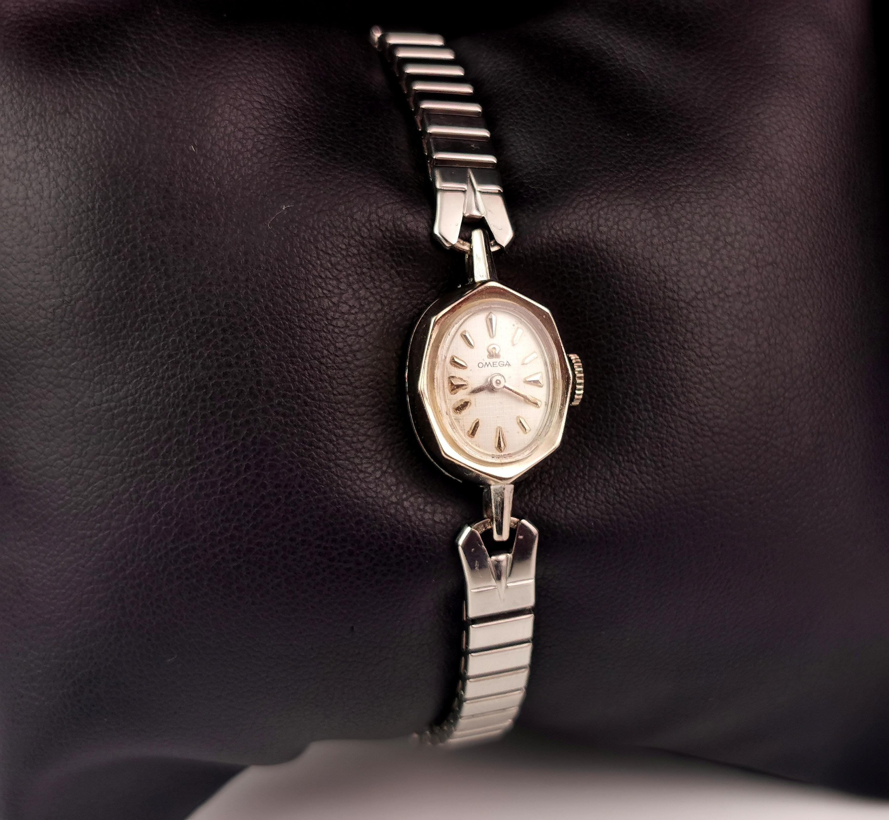 Une attrayante montre-bracelet vintage pour dames de la célèbre marque Omega.

Il s'agit d'une montre plaquée en or blanc 14ct avec un cadran argenté, des chiffres et des aiguilles noirs et une montre-bracelet à remontage manuel.

Marqué sur le