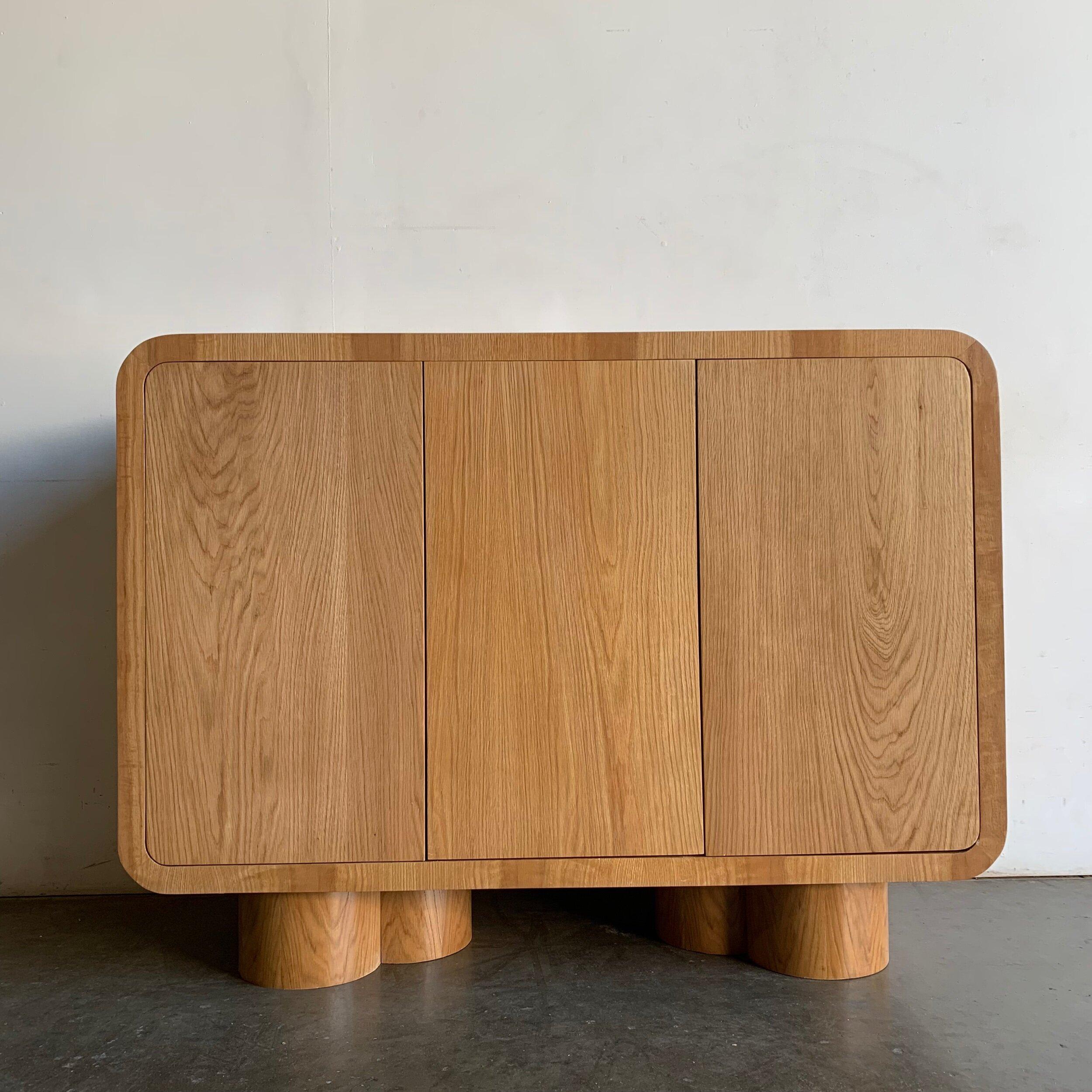 Made in house by Vintage On Point this large sideboard is made of solid and veneered white rift oak. This item features nice grain throughout , curved waterfall sides edges, sits on three merged cylinder legs, and has push open doors.