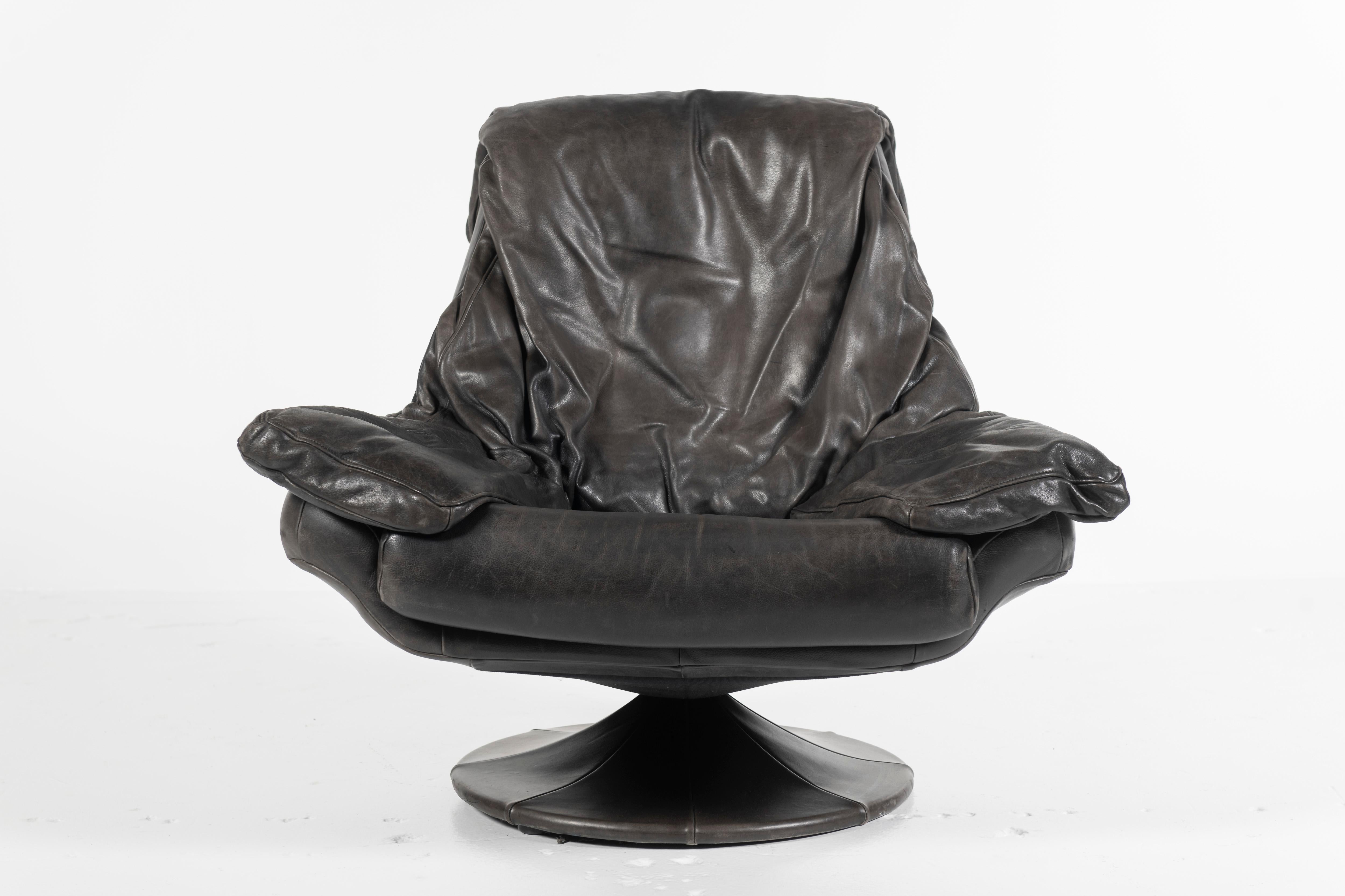Relax and enjoy your favorite beverage in this super comfortable swivel chair made in Denmark of black leather on a wooden frame resting upon a leather upholstered base. The leather has the patina you'd expect of a beloved lounge chair. Great piece