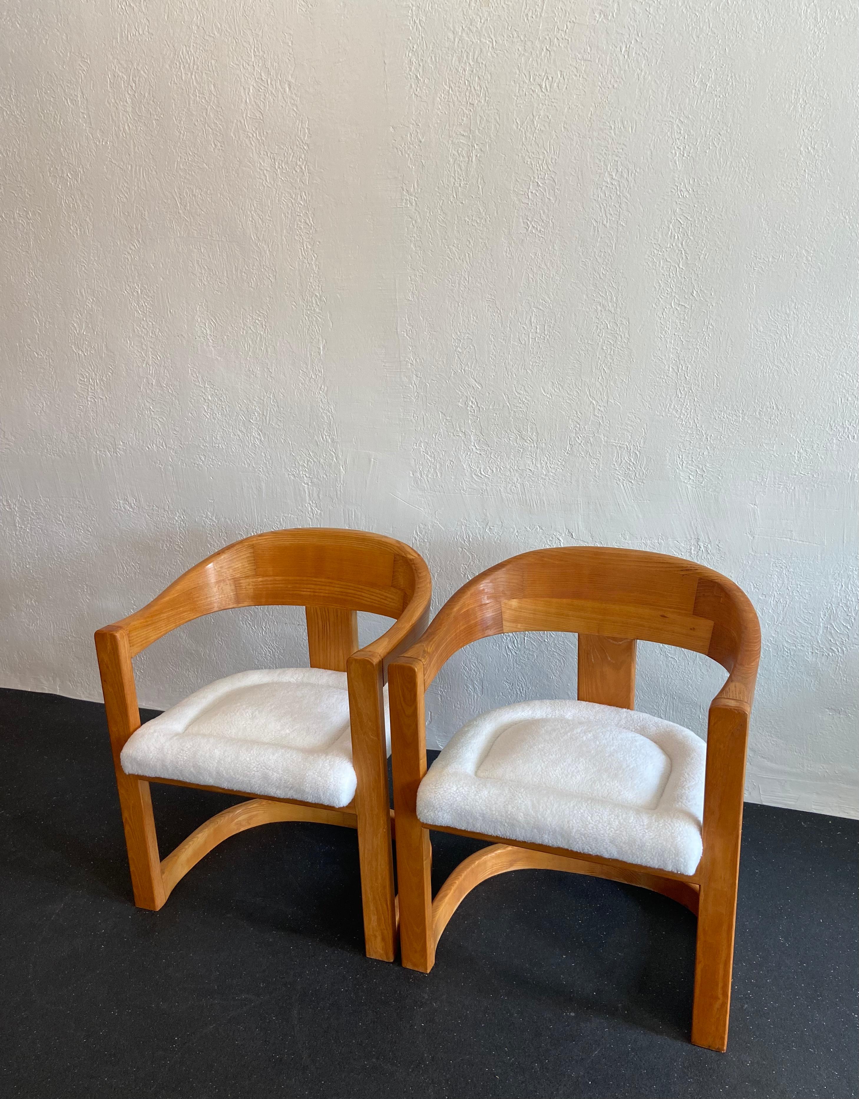 Pair of Onassis chairs in oak by Karl Springer. Updated upholstery in faux Sherpa. 

Would work well in a variety of interiors such as modern, mid century modern, Hollywood regency, etc. Piece blends seamlessly with other designers such as Warren