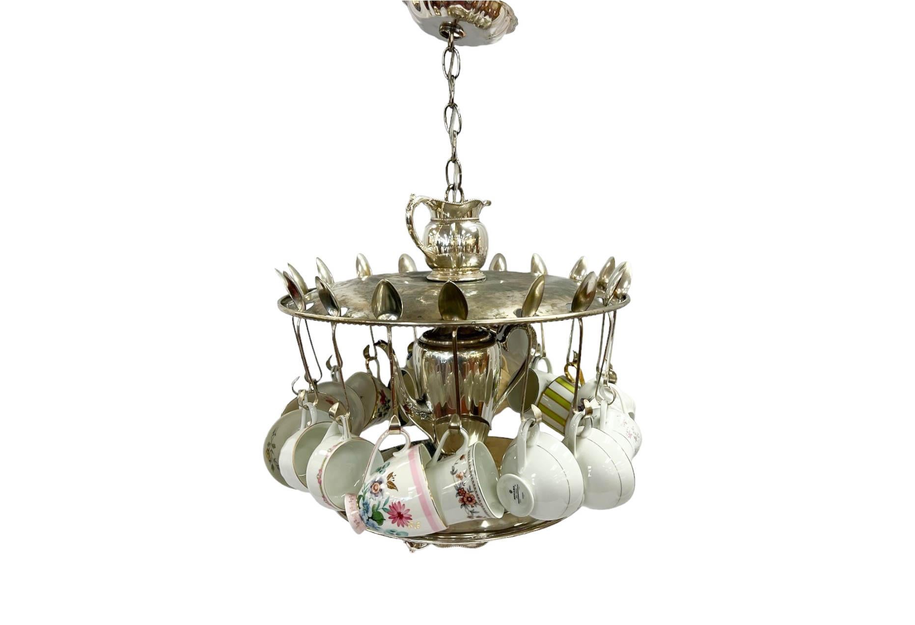 Hand-crafted novelty chandelier made entirely from silver plate service pieces, adorned with an assortment of porcelain teacups. Cups may be switched out to match your decor or rearranged as they hang freely on this fixture. The perfect chandelier