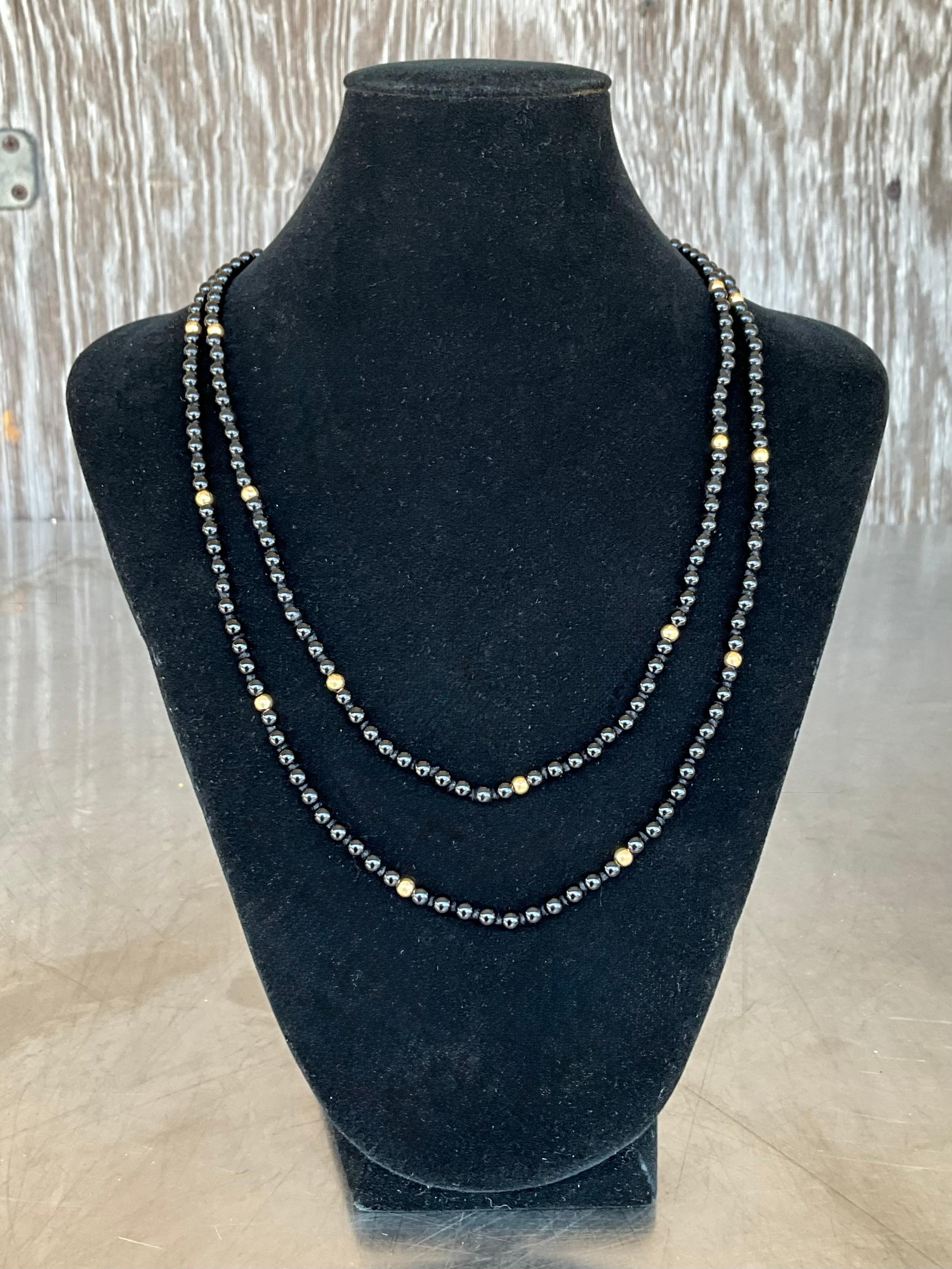 Questa collana vintage di onice e perline in oro 14k è una sofisticata miscela di eleganza senza tempo e design audace. Caratterizzata da perle di onice nere e lisce, la collana emana una bellezza raffinata e minimalista, mentre i ricchi accenti in