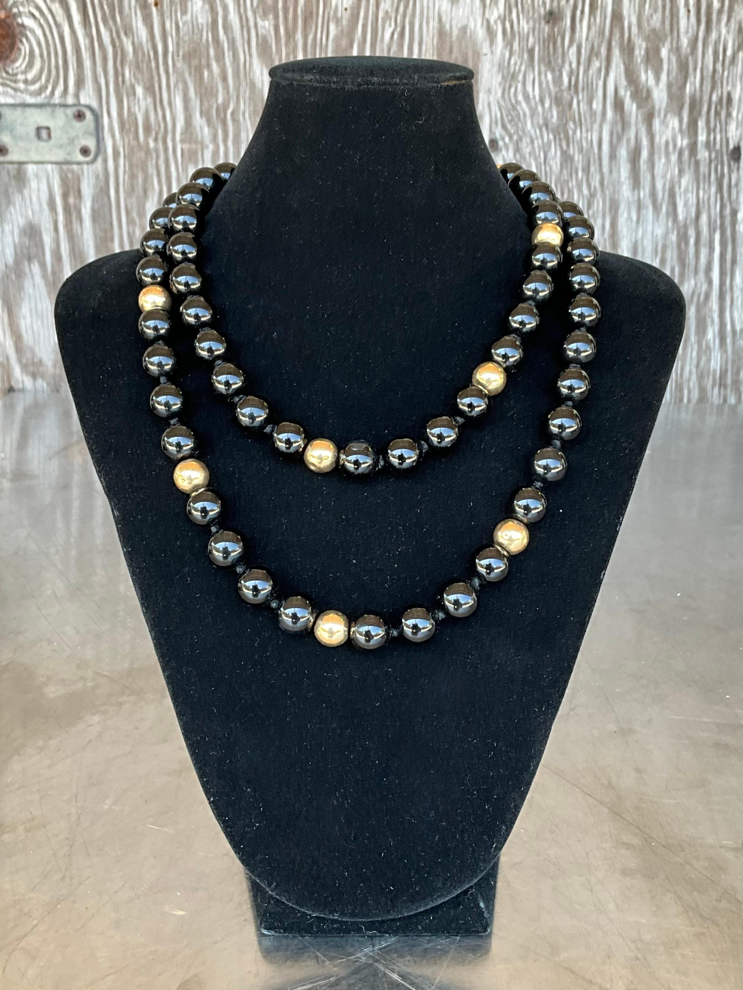 Questa collana con perline in onice vintage e oro 14k è un pezzo di lusso che bilancia perfettamente un design audace con un'eleganza senza tempo. Caratterizzata da grandi perle di onice lucidato, la collana emana una lucentezza nera e profonda che