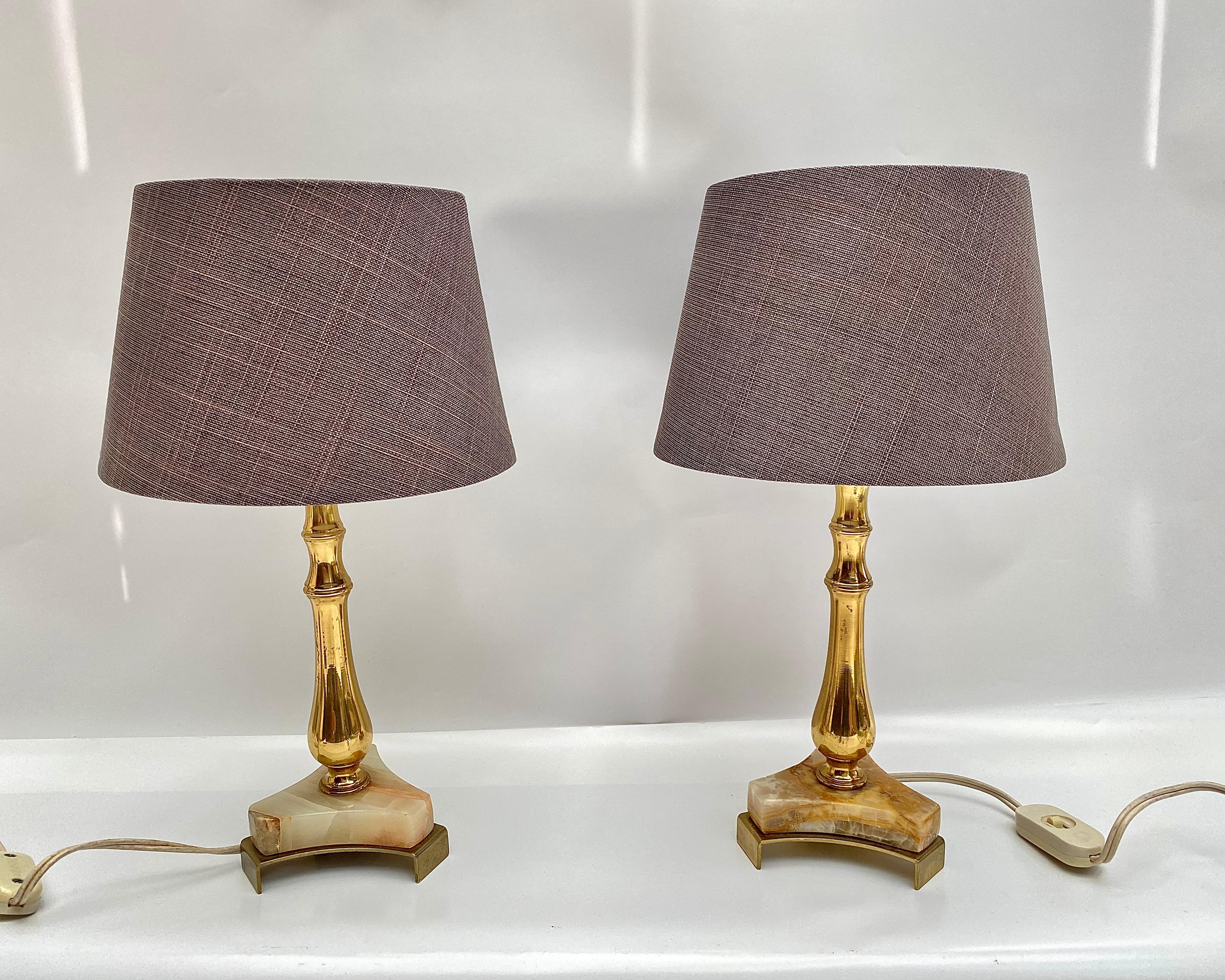 Charming pair of vintage table lamps hails from Belgium, circa 1970s.

They feature elegant bases crafted from onyx, brass, and gilt metal, topped with new, crisp shades. The combination of materials creates a luxurious and timeless aesthetic.

The
