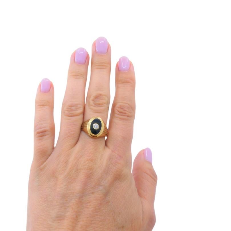 
14K gold men's signet ring, featuring a sophisticated vintage design. The ring showcases an oval-shaped black onyx stone as its centerpiece, beautifully complemented by a sparkling diamond set in the heart of the onyx. The sides of the gold band