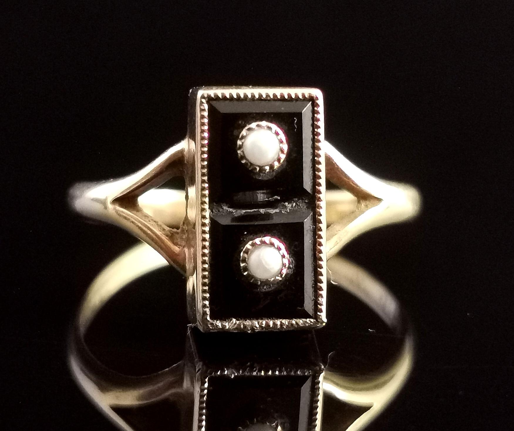 A fantastic vintage Onyx domino ring.

This amazing piece has a carved rich glossy black onyx panel to the front, rectangular in shape with a step cut to the centre.

There is a single seed pearl set in yellow gold to the top and bottom section to