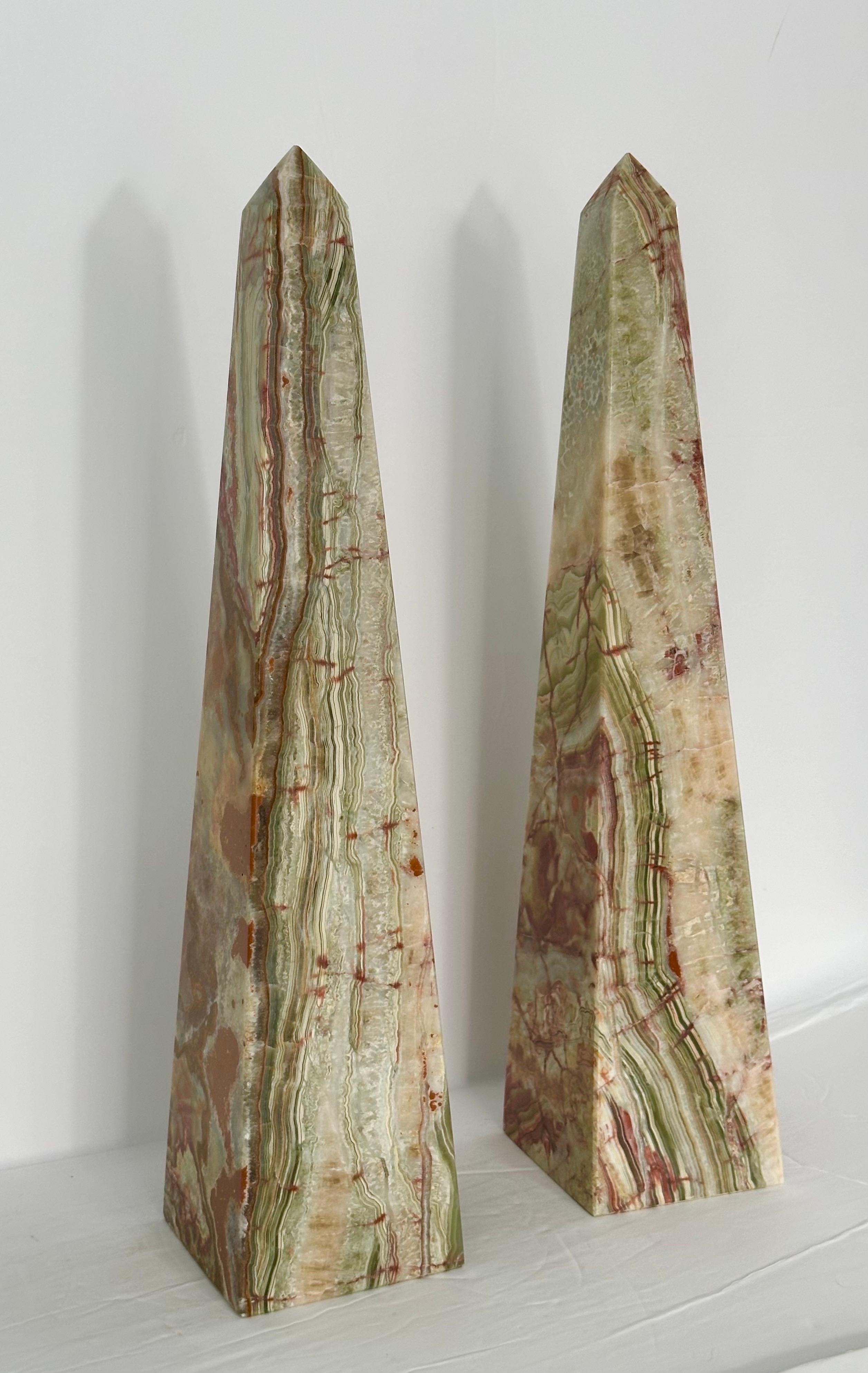 We are very pleased to offer a pair of beautiful stone obelisks, circa the 1970s.  Carved from fine onyx marble, these obelisks boast a mesmerizing color palette that includes shades of green, white, brown, and orange.  The vivid colors are