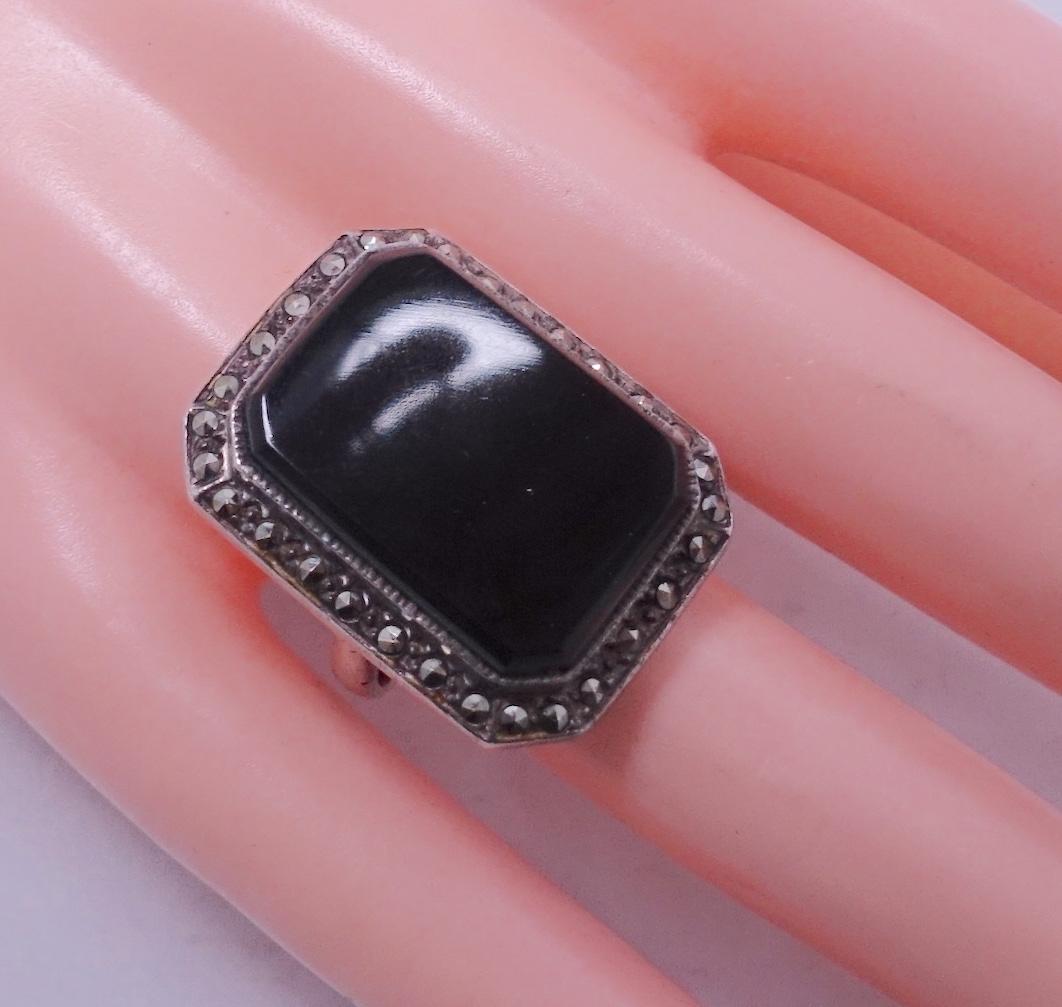 This vintage ring features a large onyx stone with marcasite accents in a sterling silver setting.  In excellent condition, this ring is a size 8 and measures 1-1/8” x 7/8”.