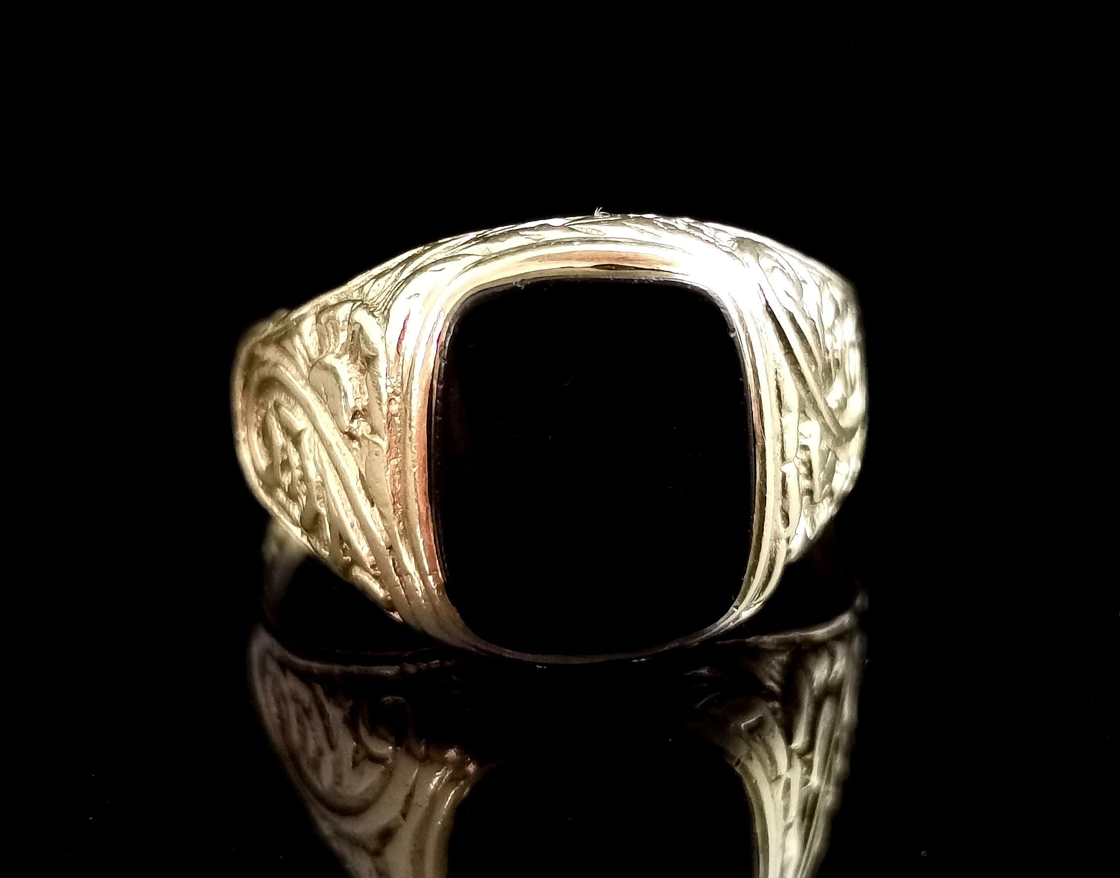 A handsome vintage Onyx signet ring in 9kt yellow gold.

This is a really grand vintage signet ring in a rich yellow gold, the decorative engraved shoulders with a floral and swirl design.

The front set with a smooth polished onyx stone, the onyx