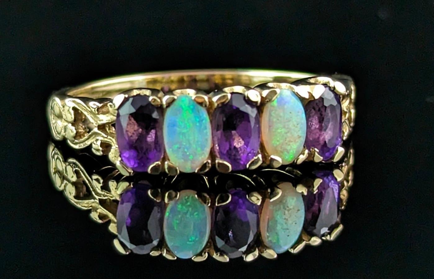 A gorgeous and vibrant vintage opal and Amethyst five stone ring.

It is a half hoop style ring in rich 9ct yellow gold with decorative heart design shoulders and a slender band.

The face of the ring is set with alternating Opals and Amethysts,