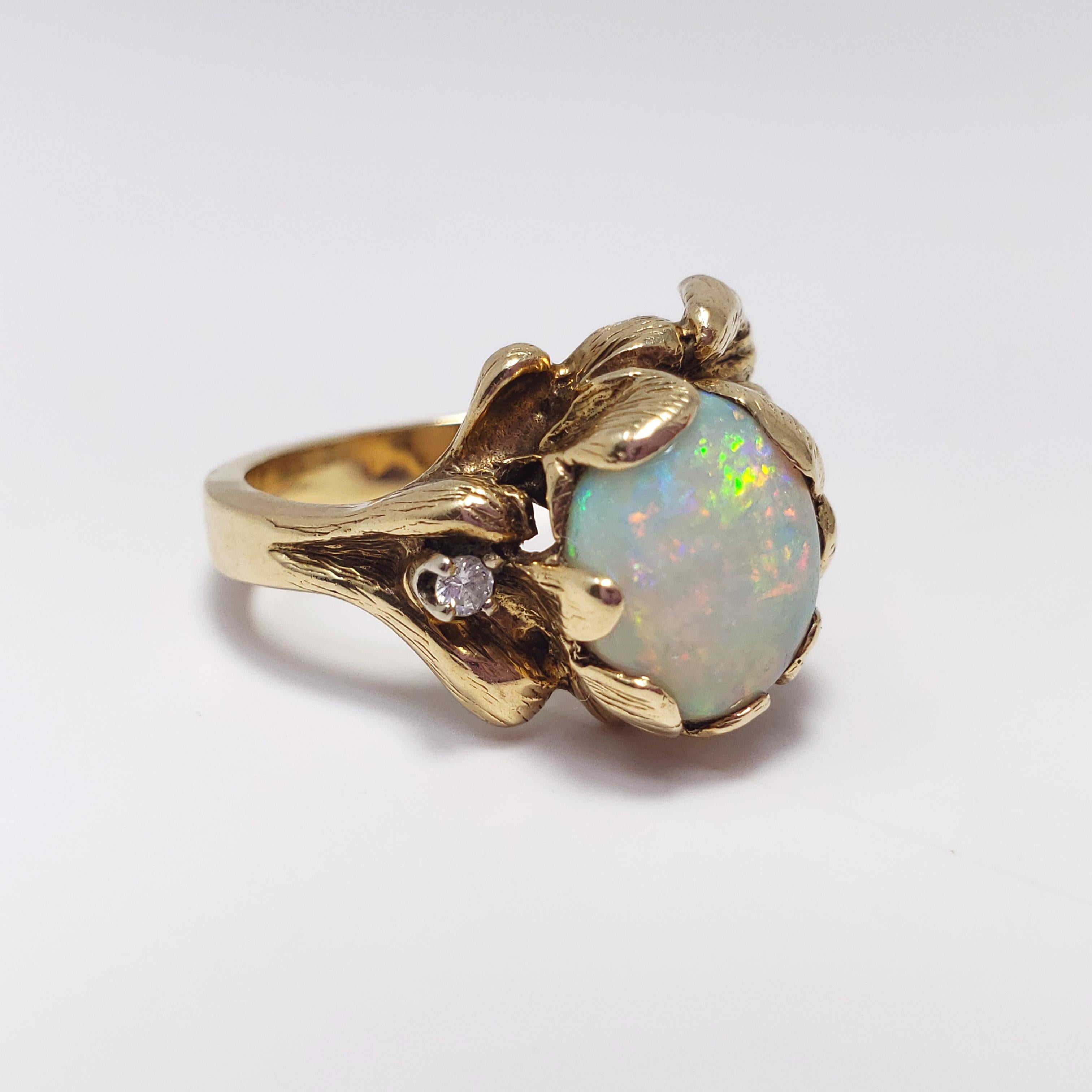 A gorgeous natural opal ring tastefully accented with a single round .01ct diamond and set in a floral-motif 14K gold band. Elegant design with a mesmerizing opal centerpiece - sure to accentuate any outfit and make a statement!

US Size 6