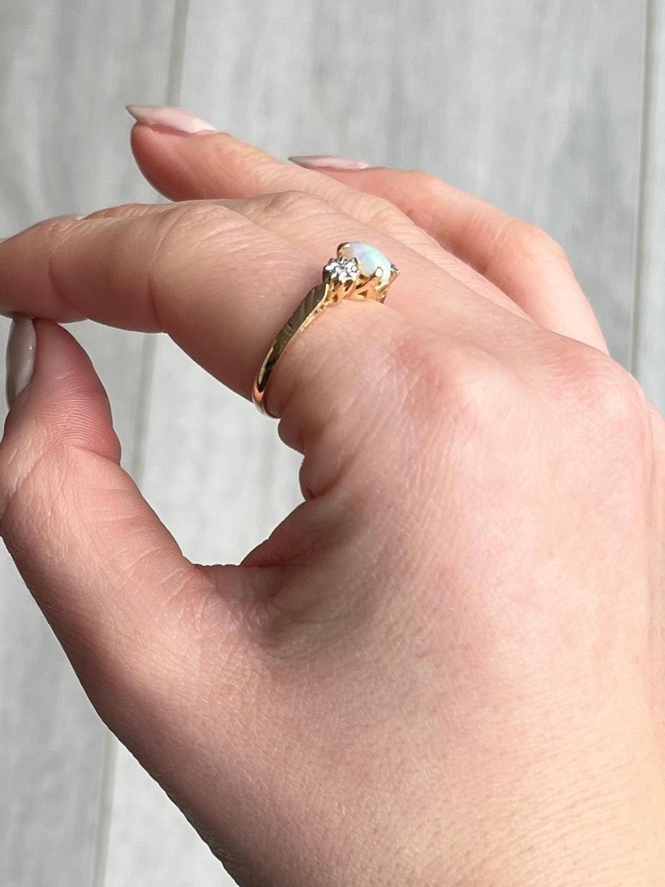 Zwischen zwei runden, funkelnden Diamanten von je 4 Pence sitzt ein wunderschöner Opal. Der Opal misst 70 pts und die Diamanten sind in Platin-Illusionsfassungen gefasst. Der Ring selbst ist aus 18-karätigem Gold modelliert. 

Ringgröße: P 1/2 oder