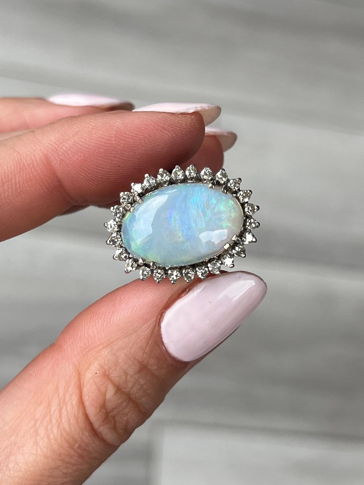 En el centro de un brillante halo de diamantes hay un precioso ópalo. El halo de diamantes totaliza aproximadamente 26 pts. Los anillos modelados en oro blanco de 9 quilates. 

Tamaño del anillo: K 1/2 o 5 1/2 
Dimensiones del ópalo: