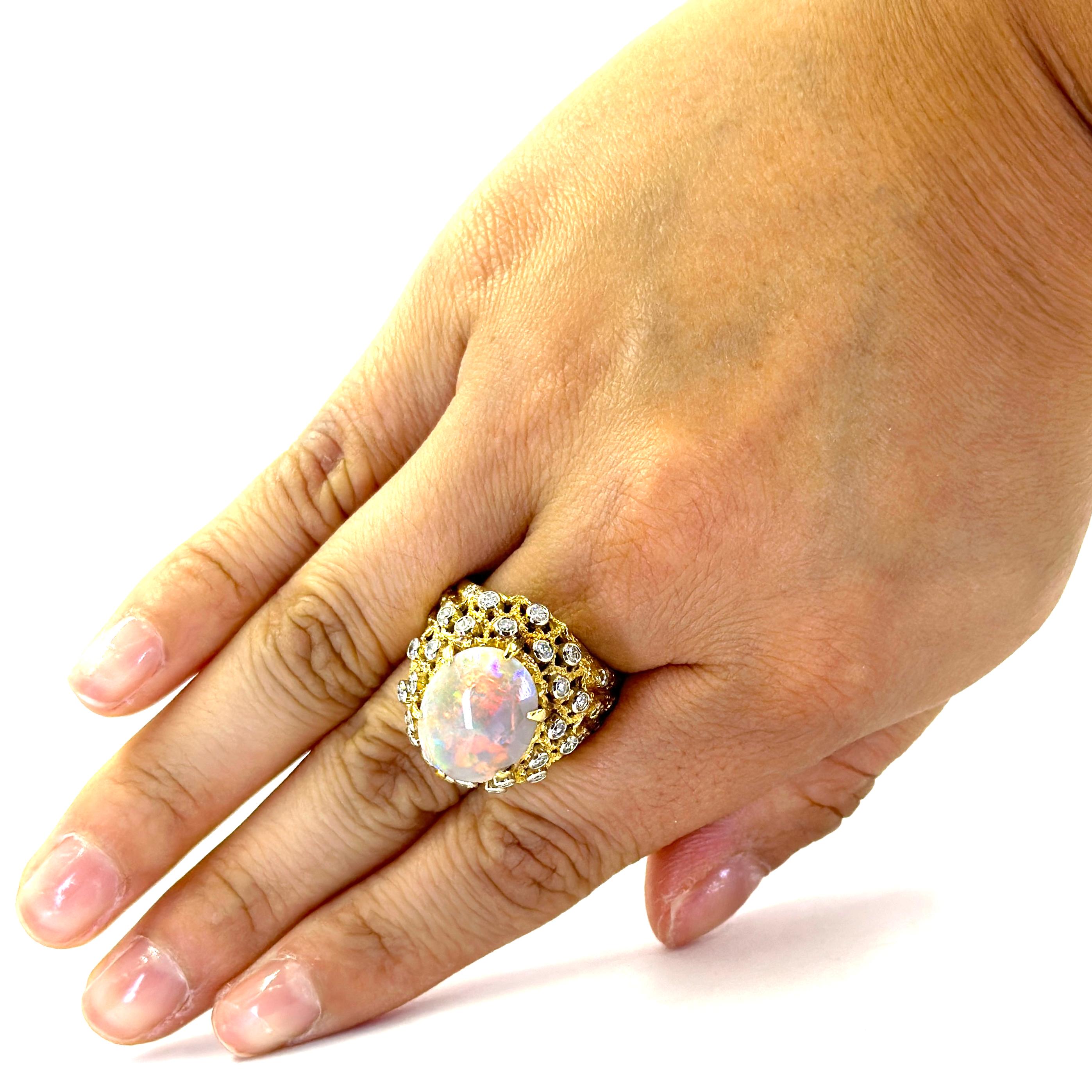 Large 18 Karat Yellow Gold Vintage Cocktail Ring Featuring A 15mm x 12mm Oval Opal Weighing Approximately 5.00 Carats with Stunning Play of Color Including Red, Purple, and Green Flashes. The Opal is Accented by 24 Round Brilliant Cut Diamonds of SI