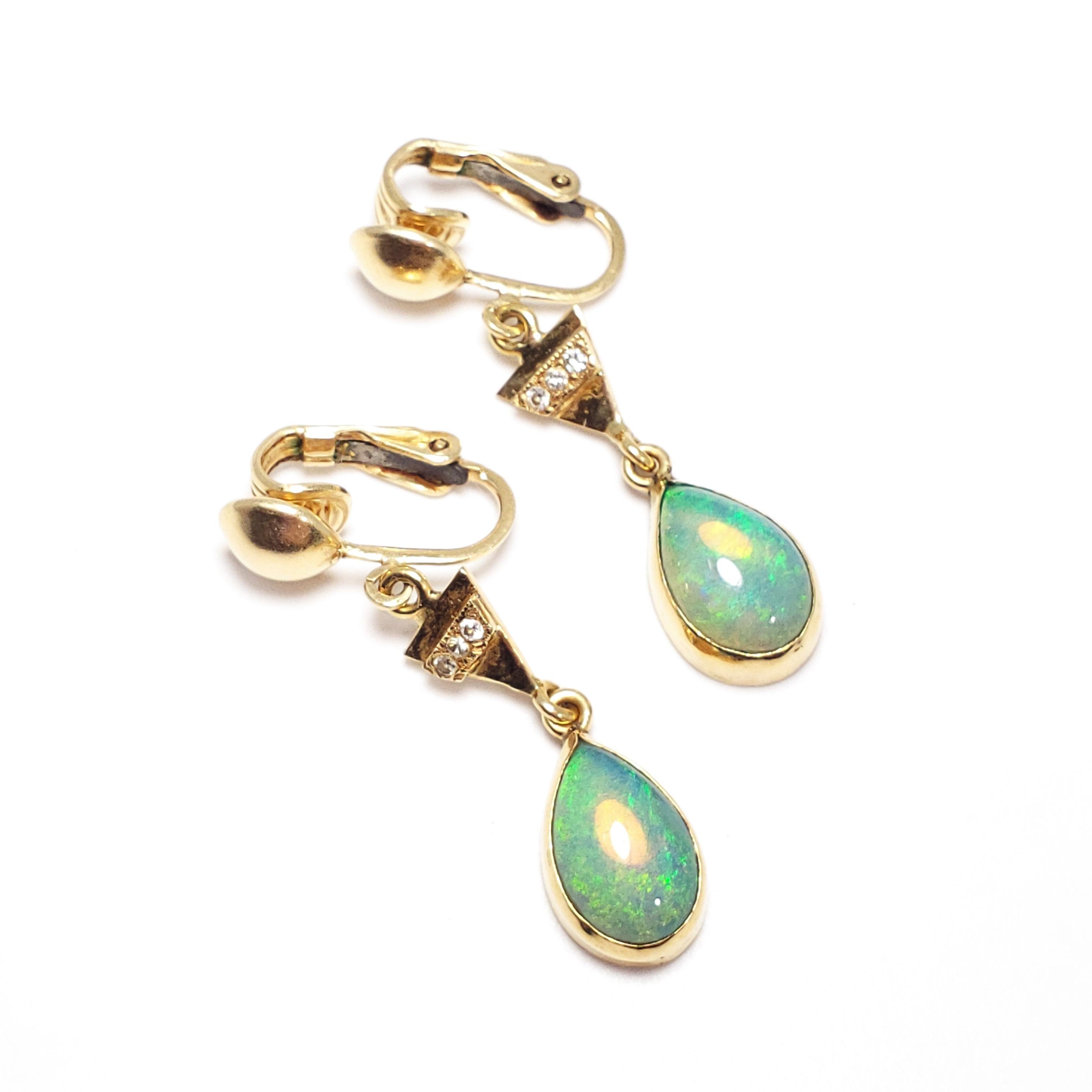 Bold and beautiful, nothing accentuates an outfit better than opals and diamonds! These two-piece dangling clip-on earrings each feature a teardrop-shaped opal set in a 14KT bezel, hanging off a triangular 14KT motif encrusted with 3 diamonds.