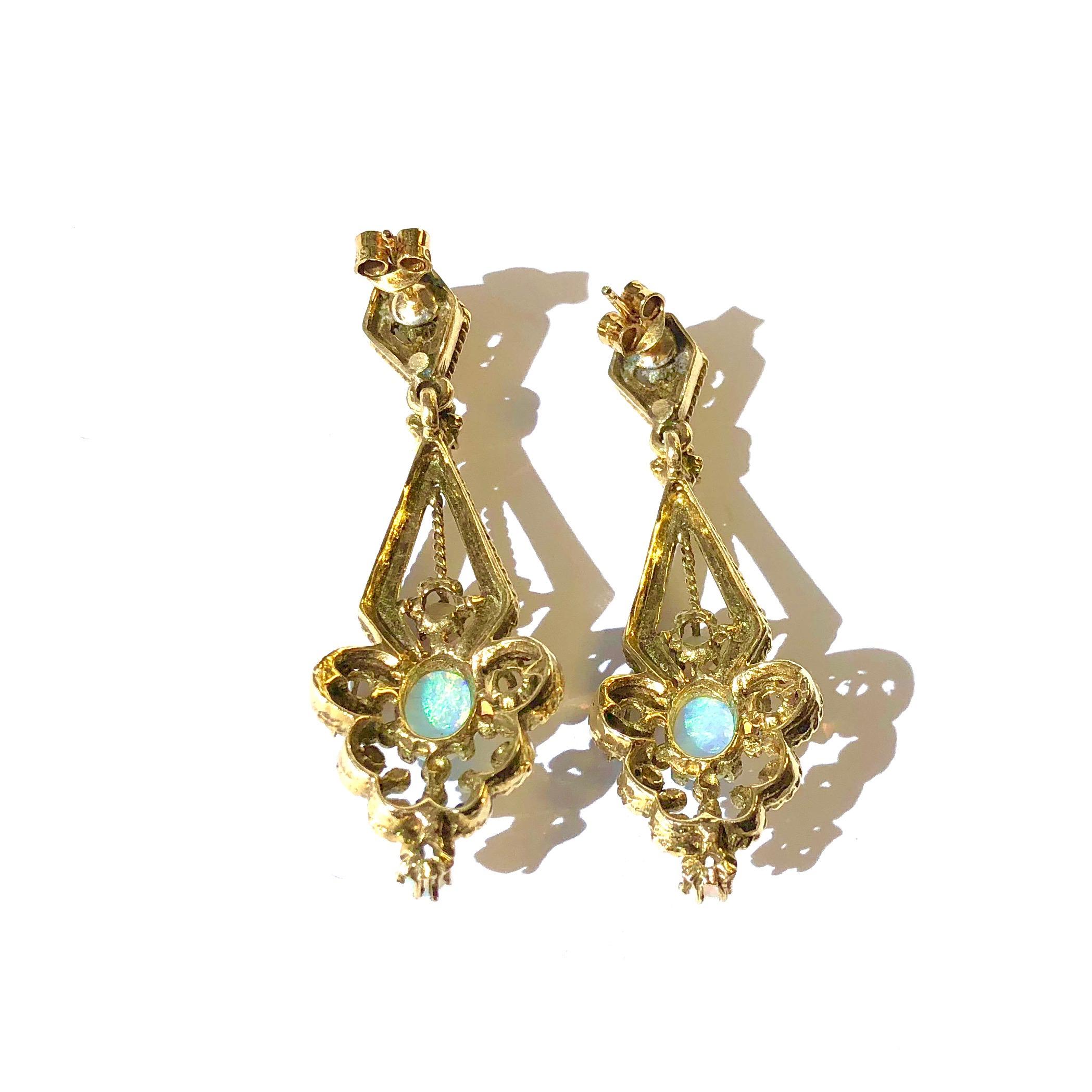 Crafted in 14K yellow gold, each earring features an elongated pendant set with seven round and oval opal cabochons. Approximate total opal weight: 2.20ct. The edges are decorated with small rope design. Post and butterfly backs. 
Measurements: 
1