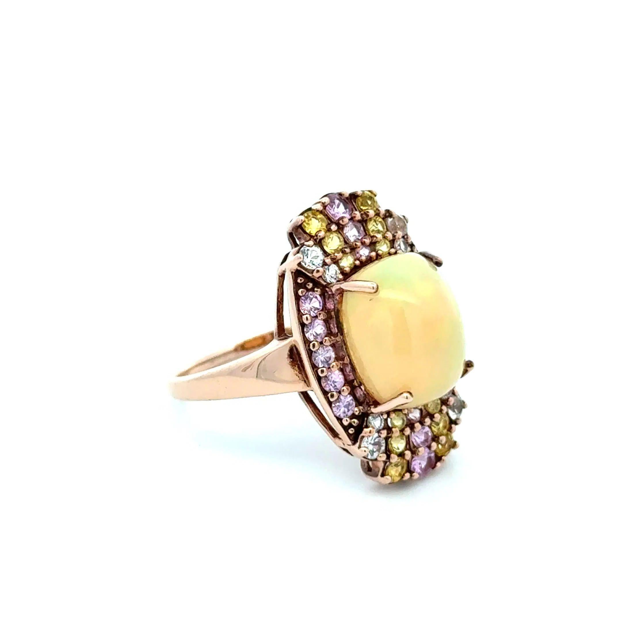 Simply Beautiful! Vintage Opal and Pink, Yellow, Blue Sapphire Gold Ring. Centering a securely nestled Hand set 3 Carat Opal. Surrounded by Pink, Yellow and Blue Sapphires, weighing approx. 1.20tcw. Hand crafted 10K Rose Gold mounting. Measuring