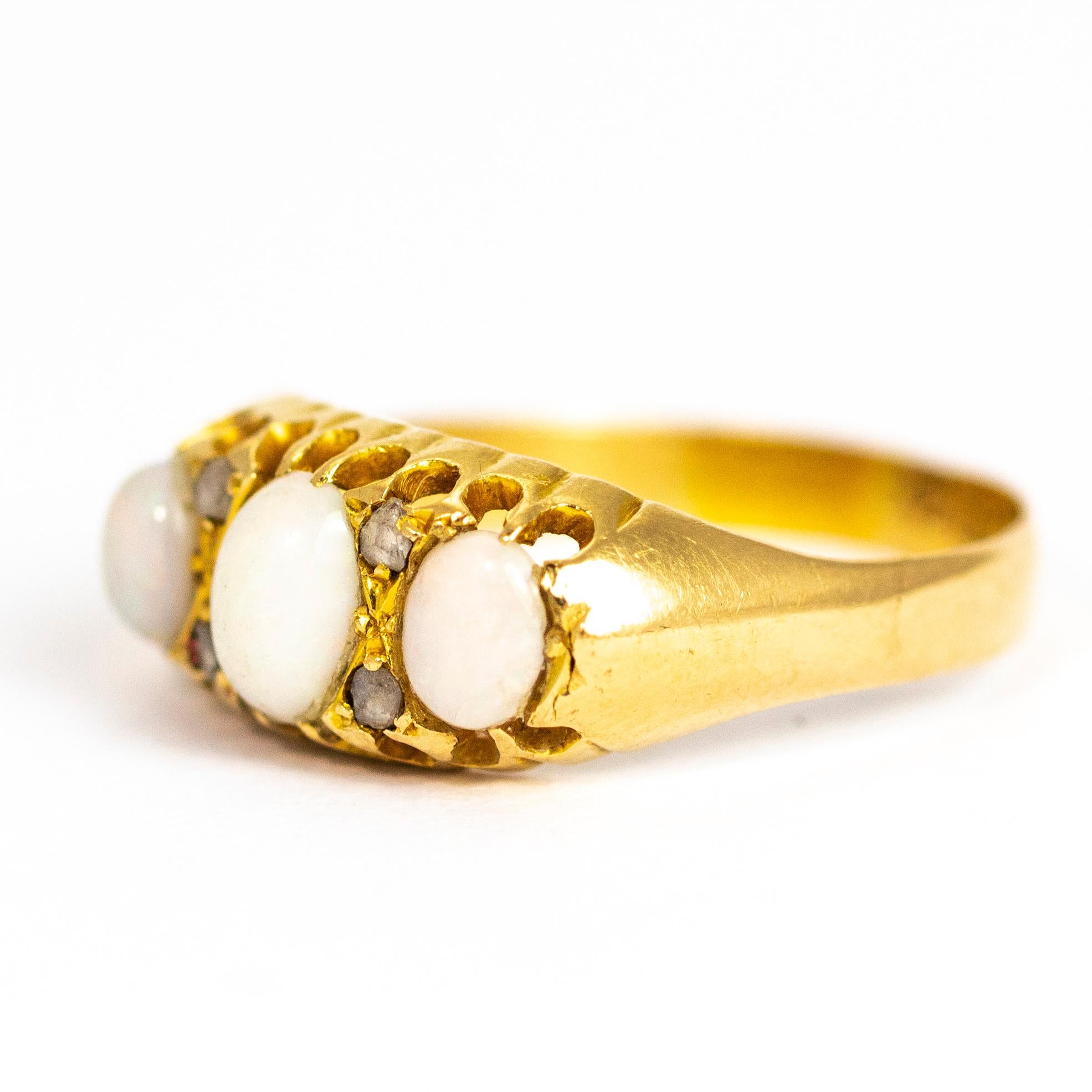Dieser bezaubernde Ring enthält drei ovale Opalsteine, zwischen denen vier Diamanten im Rosenschliff sitzen. Alle sind in einer einfachen Krallenfassung mit Kreuzdetails gefasst. Aus 18-karätigem Gold modelliert und in Birmingham, England,