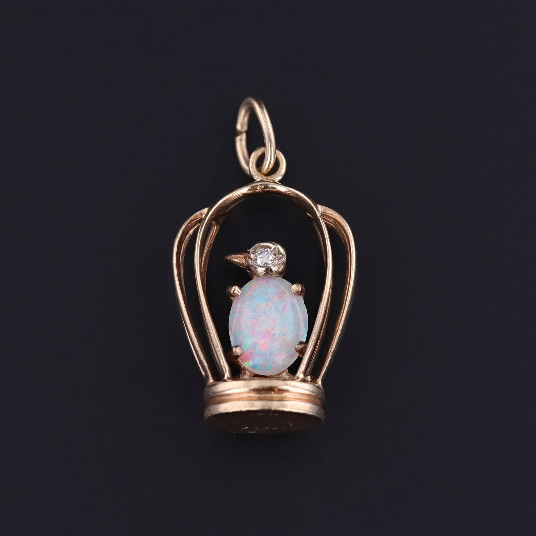 A vintage, 14k gold pendant (circa 1940-1960) featuring an opal and diamond bird inside of a birdcage.

The piece measures 1.1 inches from the top of the bail to bottom by 0.6 inches wide and weighs 4.97 grams. It is in great condition and the white