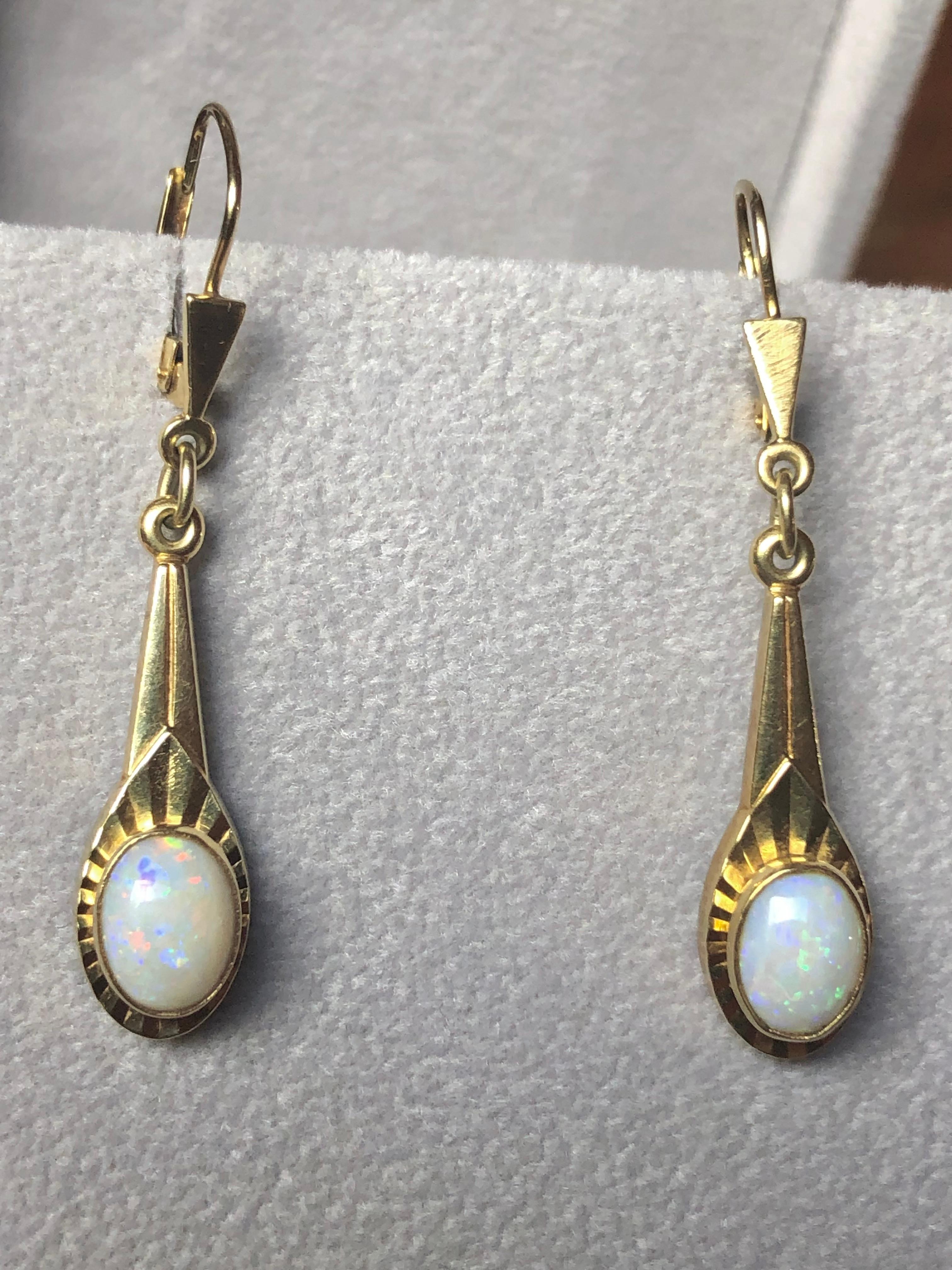Vintage! These classic dangling earrings each feature an oval-shaped opal set in a 14KT bezel, hanging off a triangular 14KT vintage motif.  Hallmarks: 14K  Length: 1.5-inch total length.  Total weight: 4.1g
