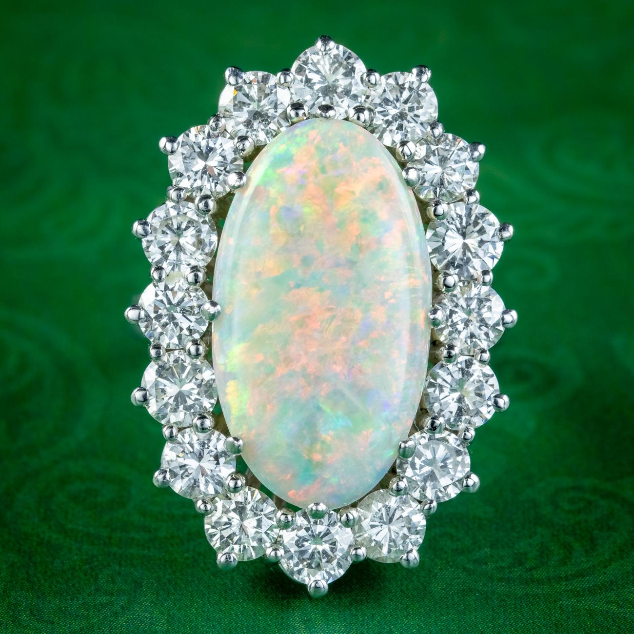 A spectacular vintage cocktail ring built around a spellbinding natural opal at its heart. It weighs approx. 12ct and displays a rainbow of vibrant colours dancing under the surface. It’s complemented by a halo of sixteen bright, clean brilliant cut