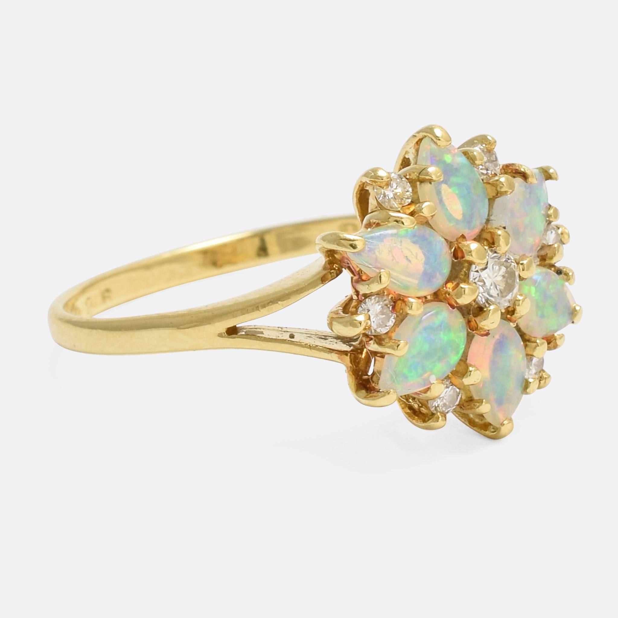 A striking vintage cluster ring set with six pear-shaped opal cabochons and seven brilliant cut diamonds. The opals are particularly bright, seemingly bursting with colour, and the diamonds are sparkly and white. The stones rest in a basket gallery