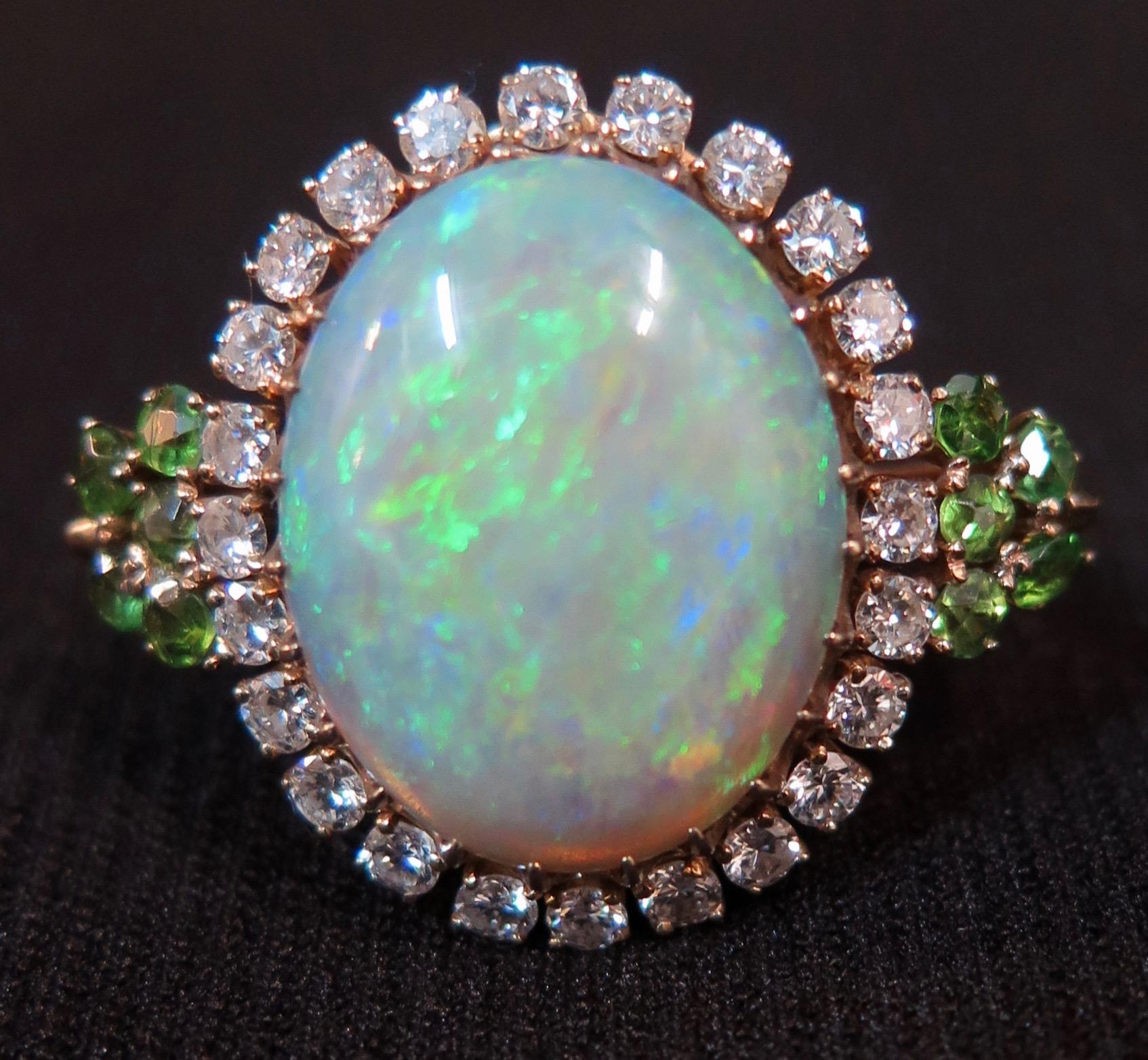 This vintage mid-20th century ladies gem stone ring is designed in 14-karat gold with a magnificent opal, diamonds & peridots. The 8 carat oval cabochon blue/green opal is without flaws and has vibrant color with lustrous accents. This wonderful gem