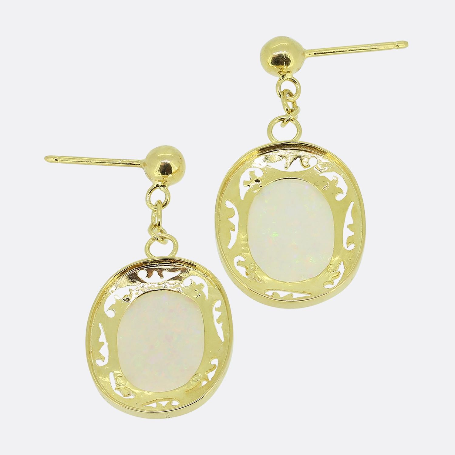 Here we have a wonderful pair of opal drop earrings. Each identical vintage piece has been crafted from 18ct yellow gold with a four-clawed setting playing host to a single oval shaped white opal showcasing colourful flashes of reds, blues and