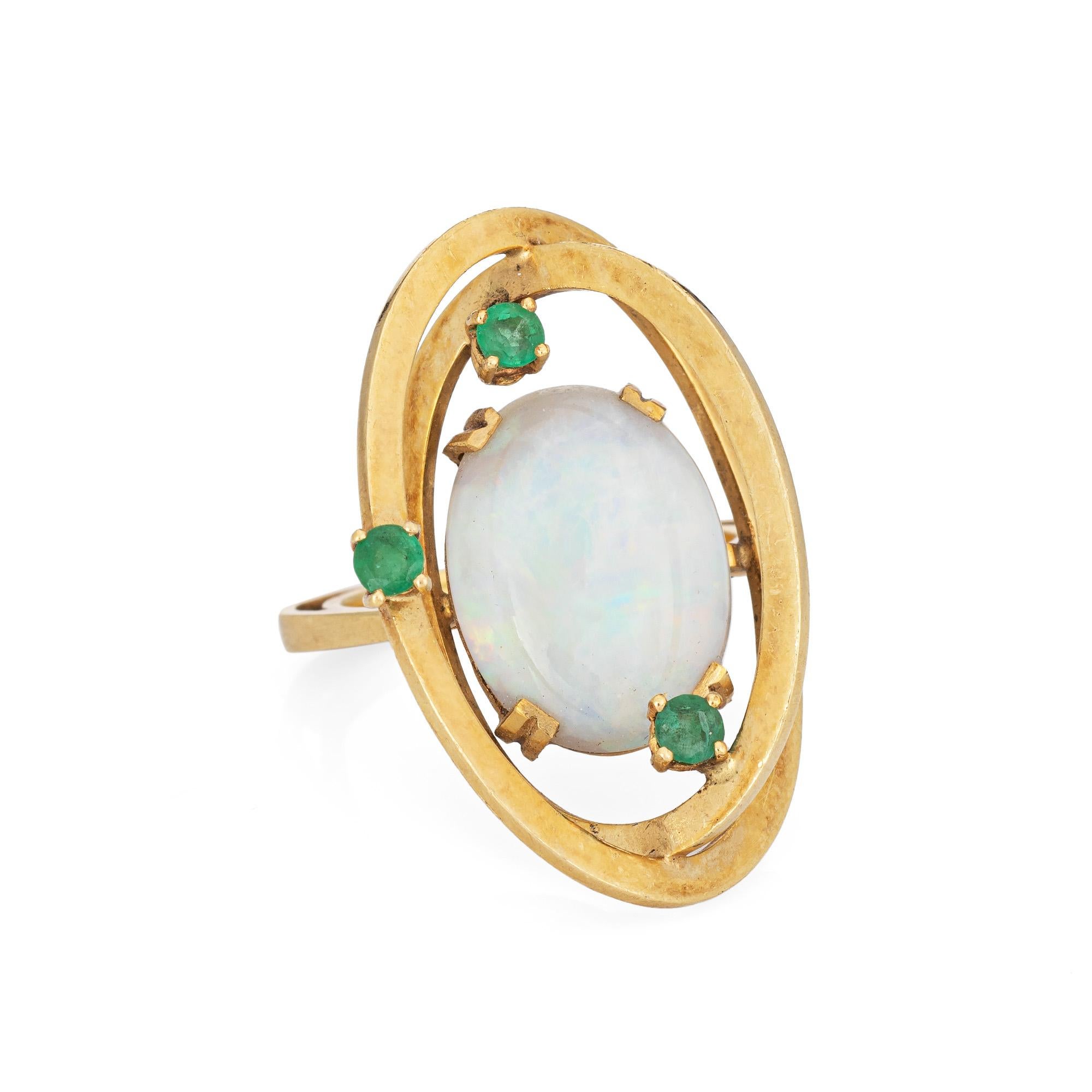 Stylish vintage opal & emerald cocktail ring crafted in 18 karat yellow gold (circa 1960s to 1970s). 

The center opal measures 16mm x 12mm (estimated at 4 carats), accented with three estimated 0.03 carat emeralds.  The opals is in very good