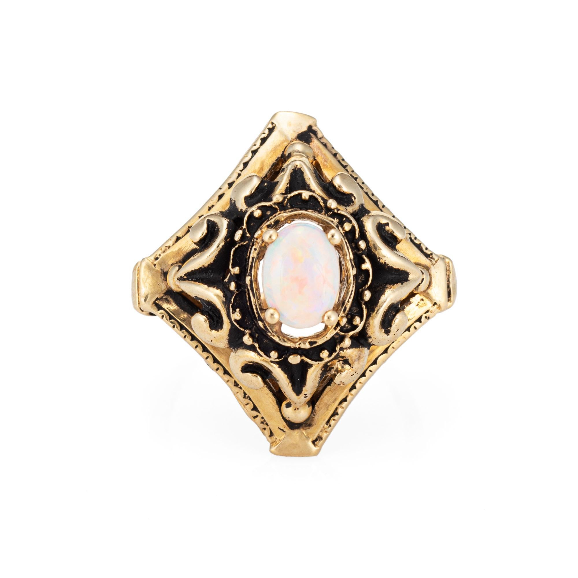Stylish vintage opal cocktail ring crafted in 14 karat yellow gold (circa 1960s to 1970s). 

Center set opal measures 6mm x 5mm.  

The natural opal shows green to purple, orange, yellow and bits of red color flashes. The mount has a layered design