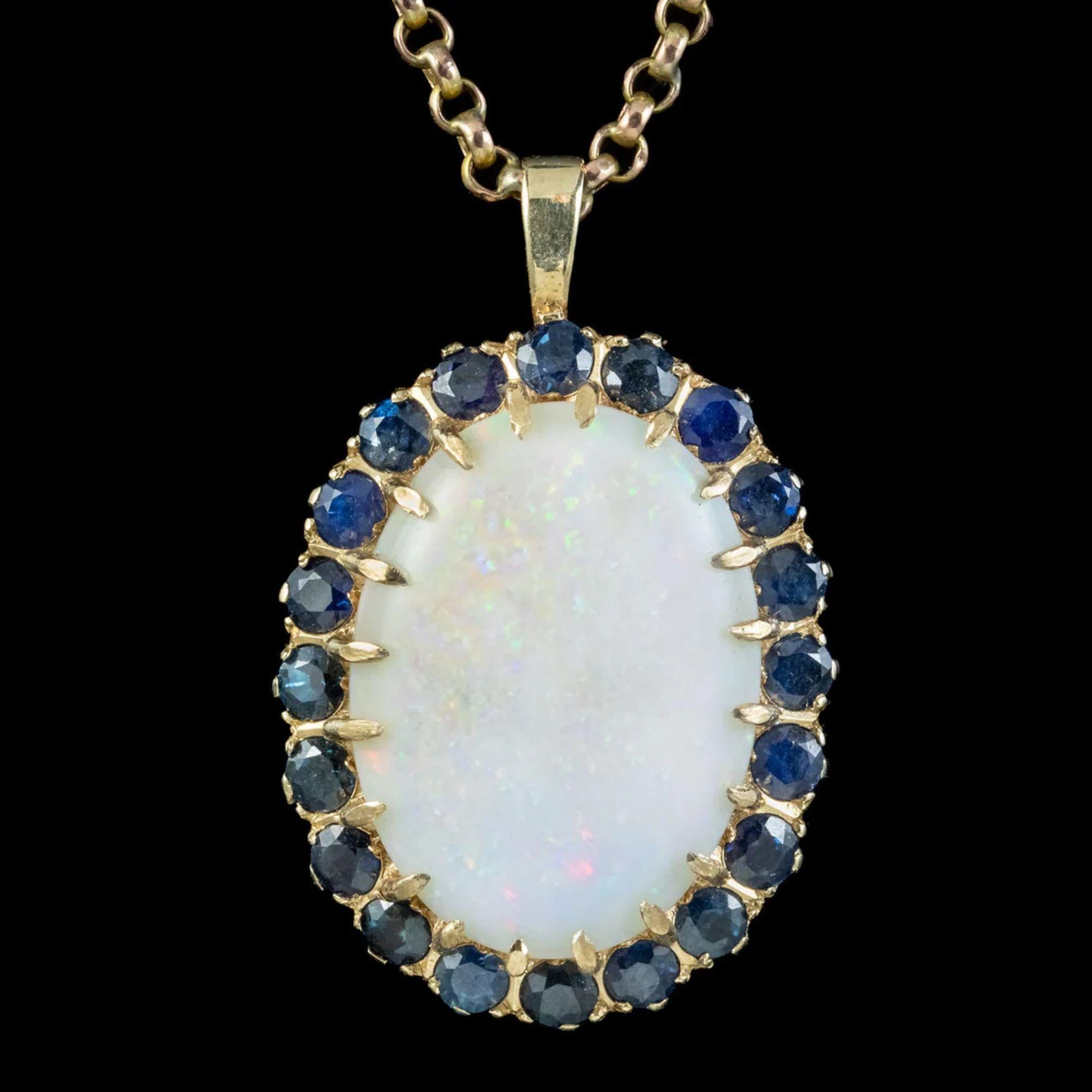 Dieser bemerkenswerte Anhänger besteht aus einem großen natürlichen Opal mit einem Gewicht von ca. 25 Karat. Er glänzt mit einem Regenbogen aus farbigen Sprenkeln und ist in der Mitte eines Halos aus blauen Saphiren gefasst, die jeweils ca. 0,15ct
