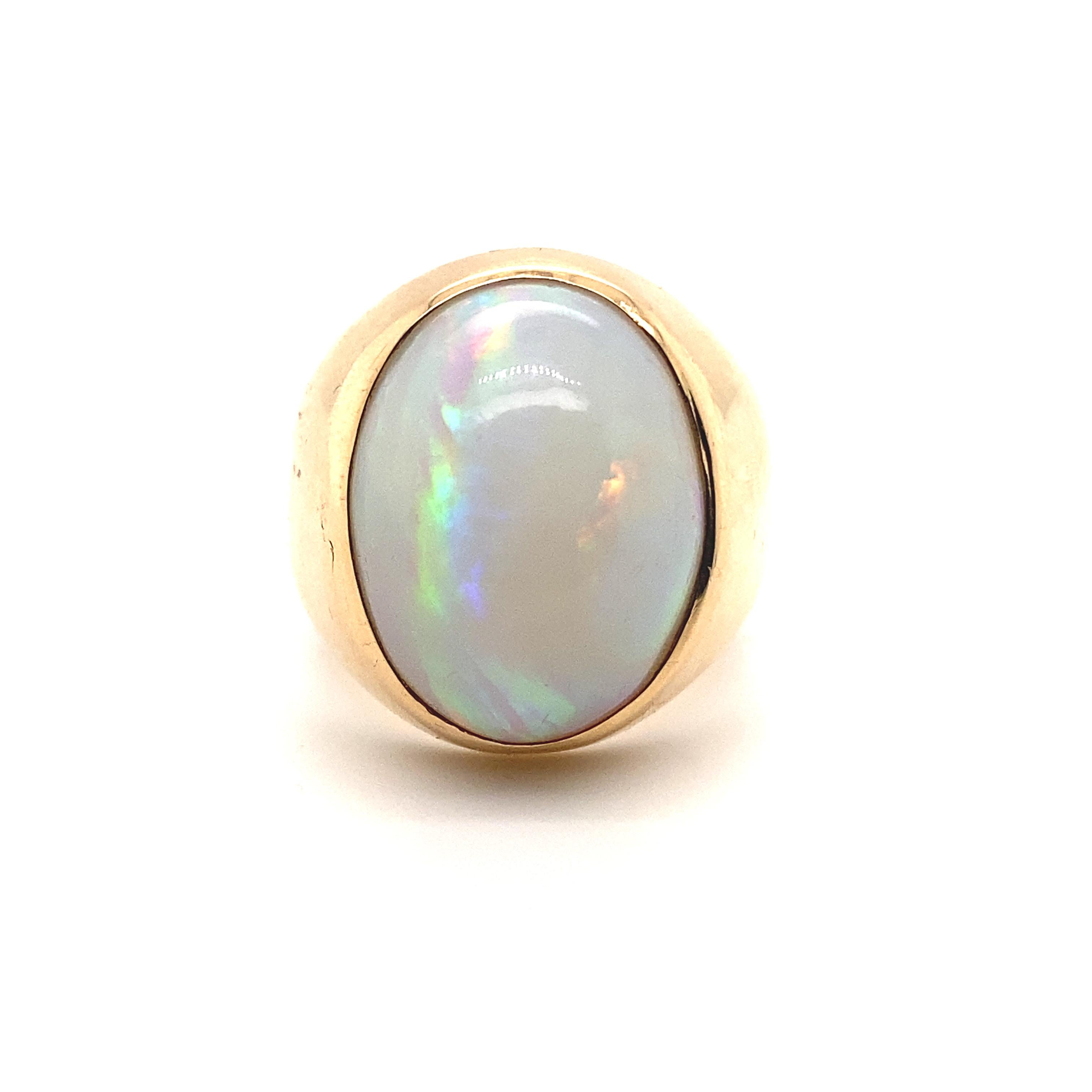A vintage opal signet ring in 18 karat yellow gold, circa 1960.

This elegant ring is set to its centre with an exceptional oval shaped cabochon opal which is perfectly framed by a plain polished bezel set 18 karat yellow gold mount.
The opal