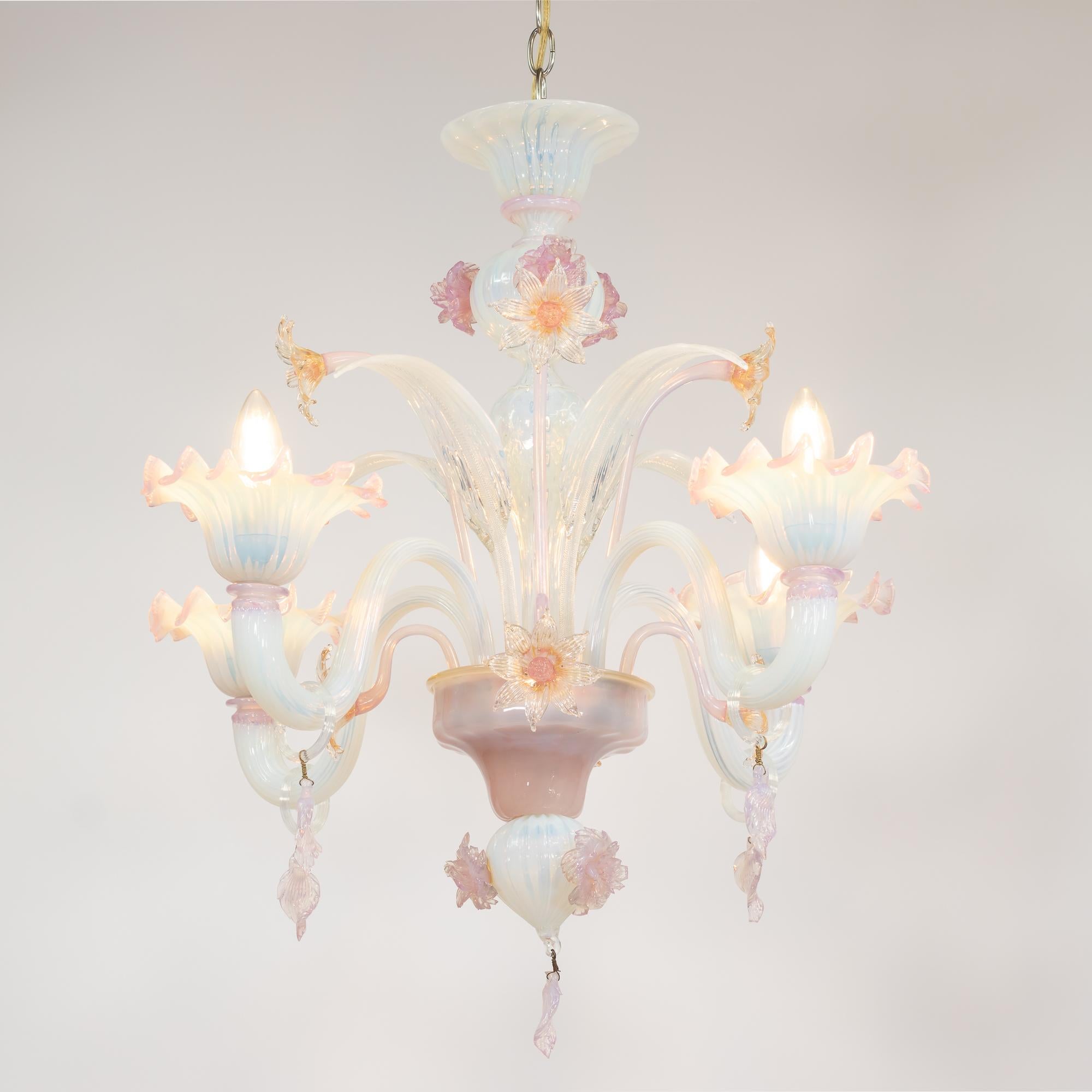 Questo lampadario di Murano opalino e floreale in stile barocco ha cinque graziosi bracci a voluta che sorreggono bobeches a forma di fiore. Questi bobeches di opalino lattiginoso hanno anche un fuoco tenue blu-lilla e mostrano nervature ottiche