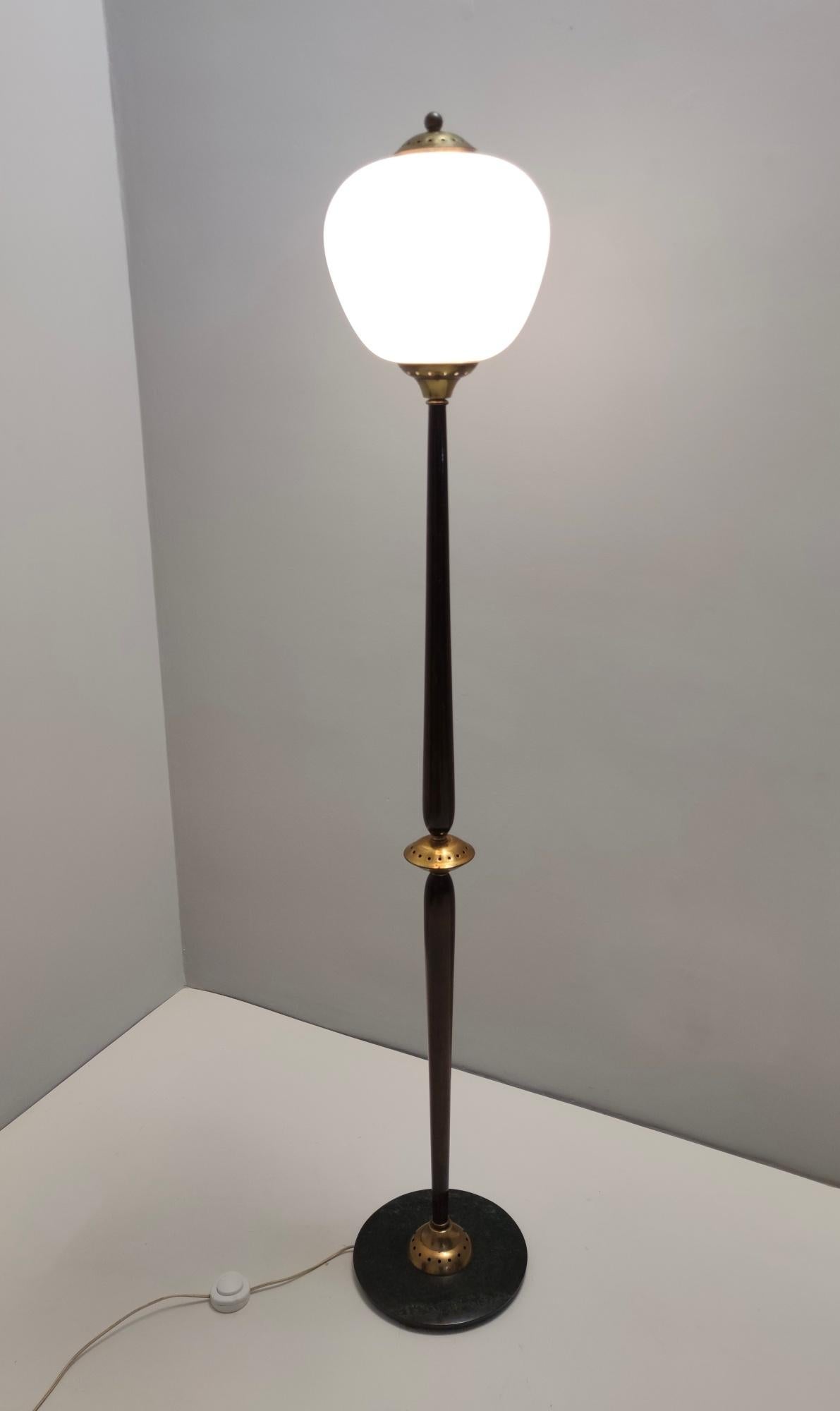 Made in Italy, 1950s. 
This beautiful floor lamp features a beech stem with brass details, a marble base and an opaline glass lampshade.
It is a vintage piece, therefore it might show slight traces of use, but it can be considered as in very good