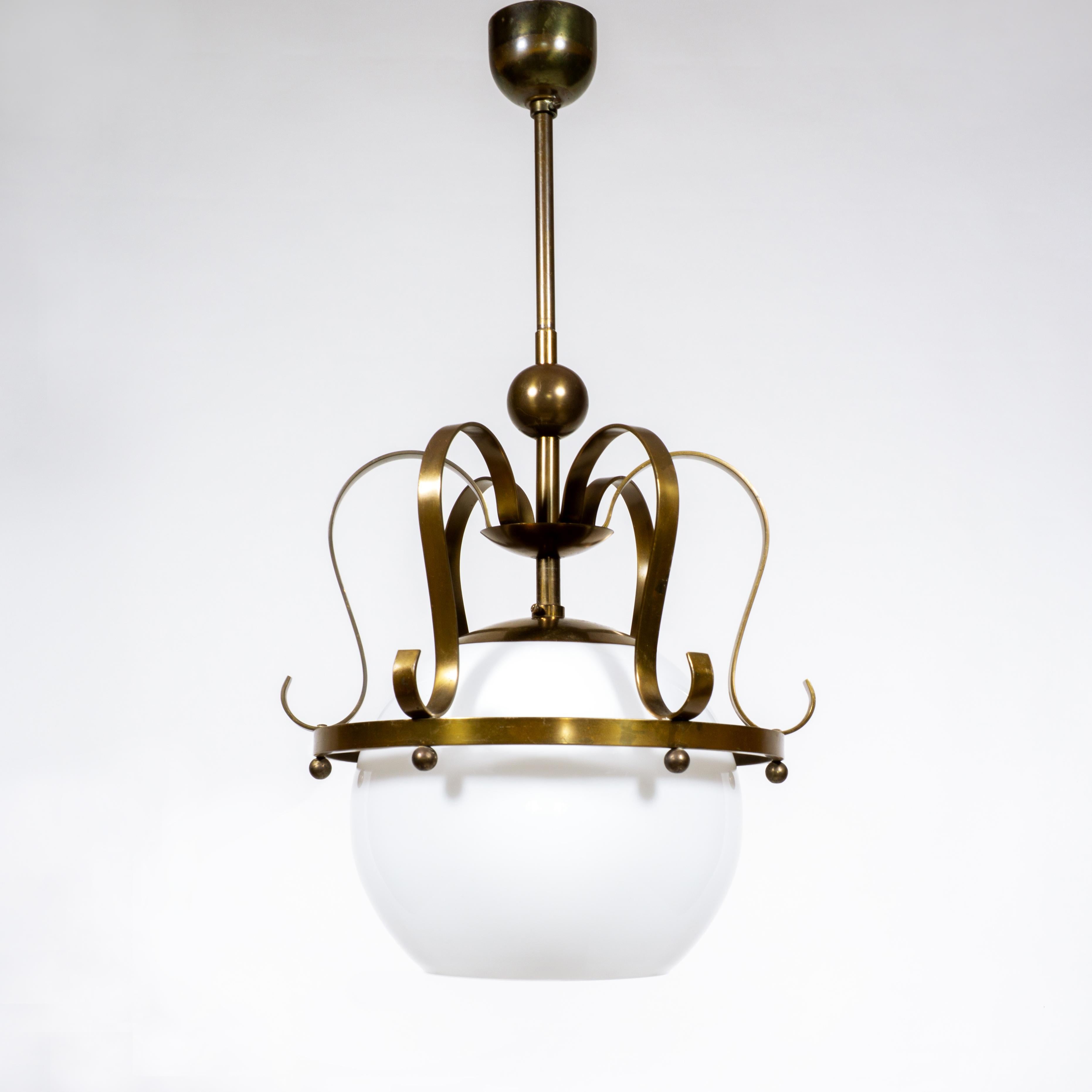 Diese äußerst dekorative Pendelleuchte im Hollywood-Regency-Stil ist aus massivem Messing und Opalglas gefertigt und stammt aus den 1960er Jahren. Der Glasschirm dieser wunderschönen Lampe wird von einem kronenartigen Messingrahmen gehalten, der mit