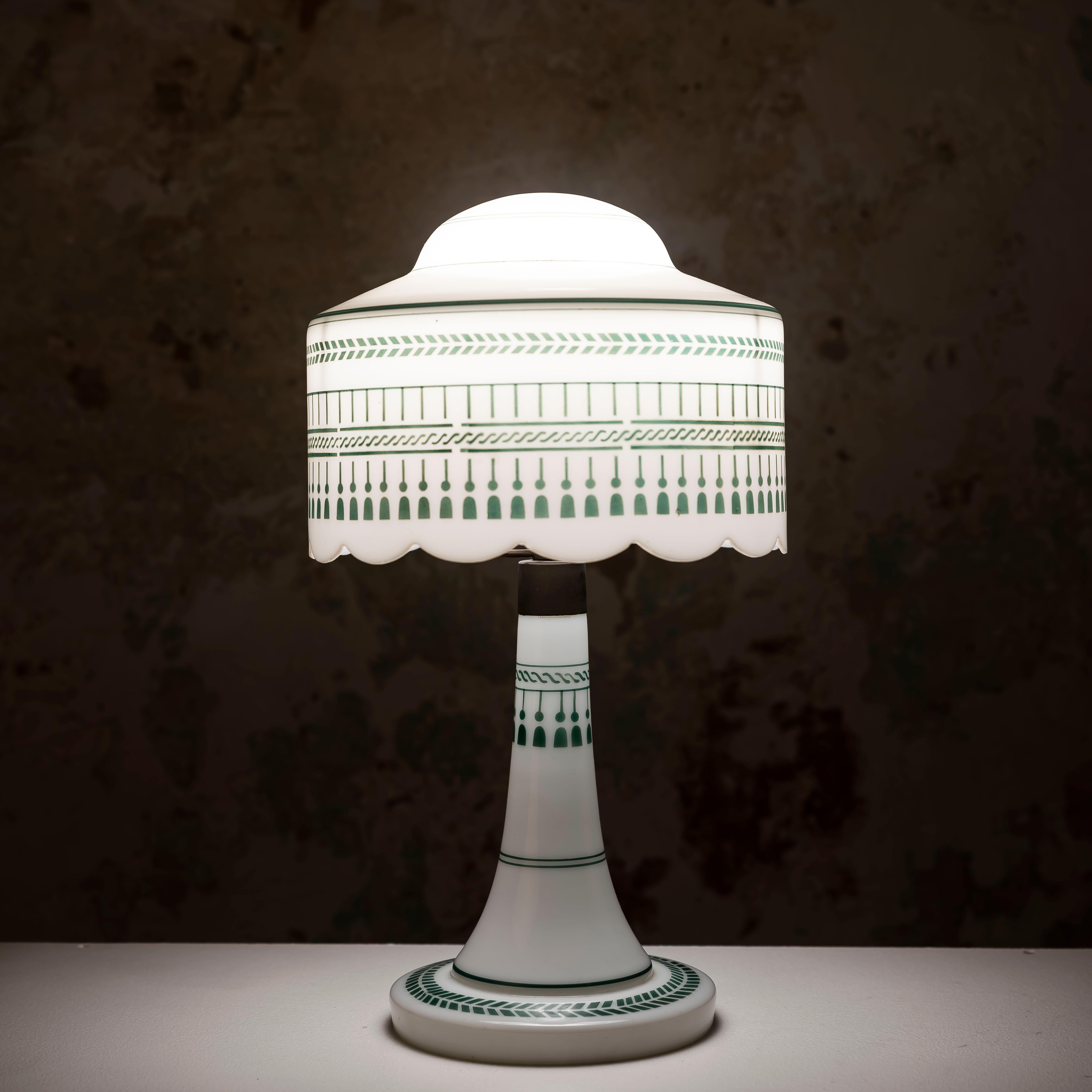 La lampada da tavolo Vintage Opaline con decorazioni verdi è un pezzo accattivante che porta a casa tua una squisita miscela di stili Art Déco e Secessione Viennese. Questa lampada è una testimonianza dell'eleganza e della raffinatezza del design