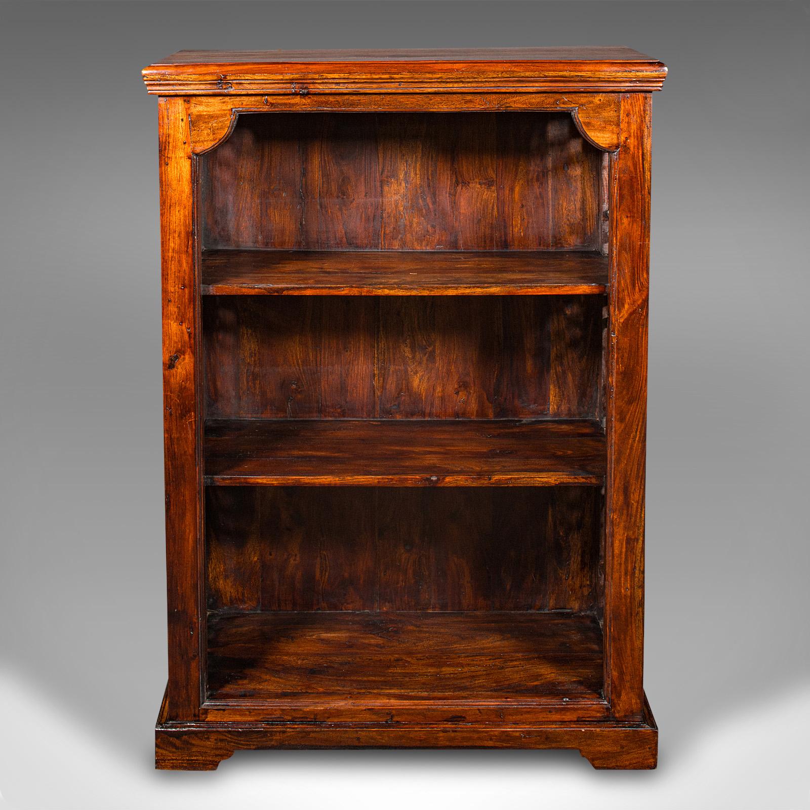 This is a vintage open bookcase. An Asian, stained Hevea and cast iron shelving unit in Regency and Colonial revival taste, dating to the late 20th century, circa 1980.

Imposing and substantial, with generous shelf space
Displaying a desirable aged